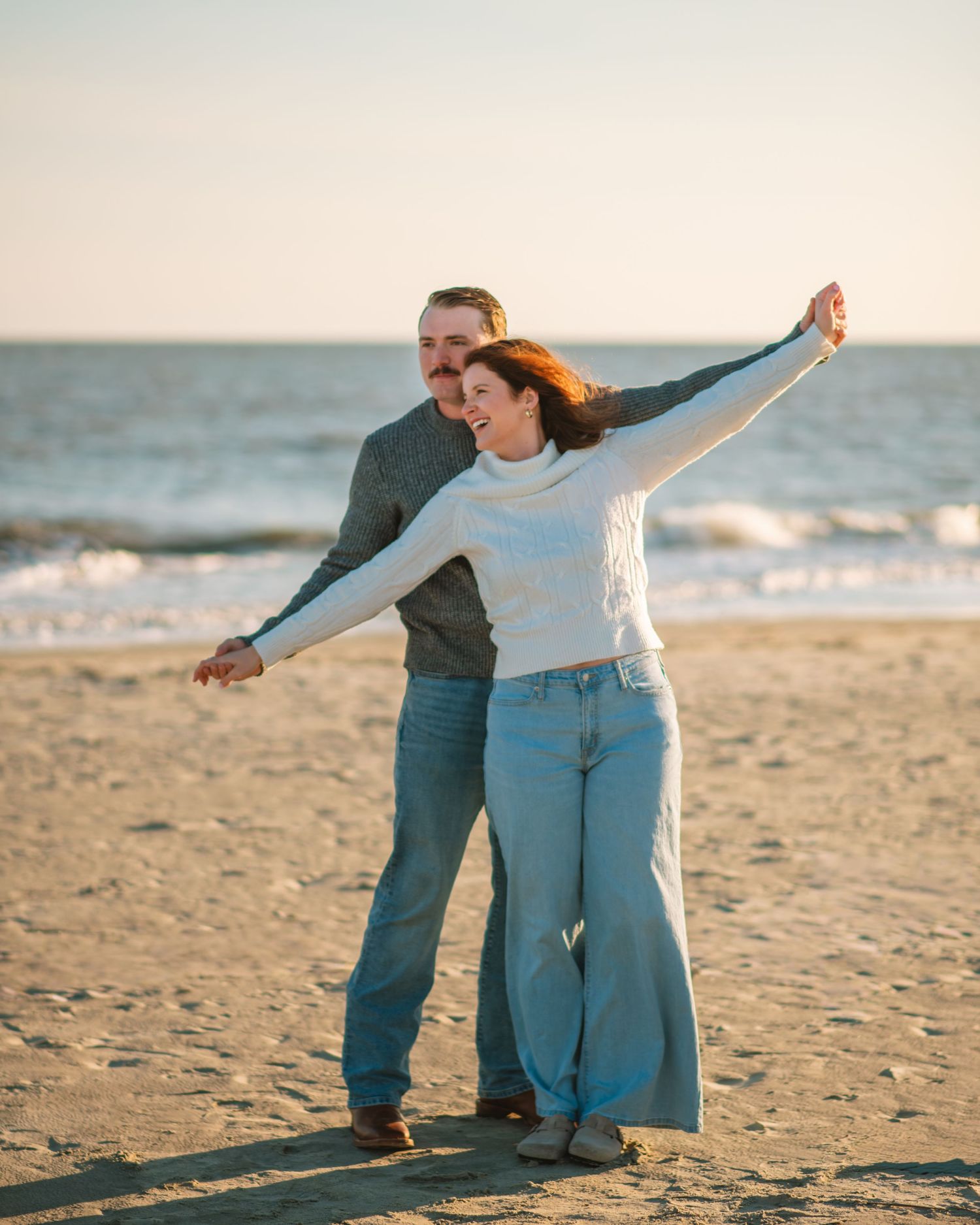 Couple spinning together on beach during a fun and carefree engagement session. on Sullivans Island, Charleston SC