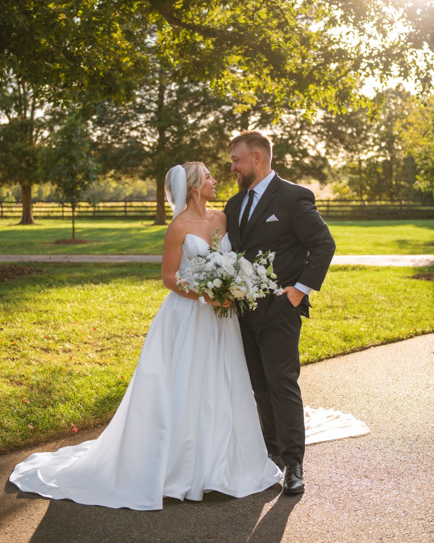 Bride and groom standing together outdoors during a golden hour wedding portrait.