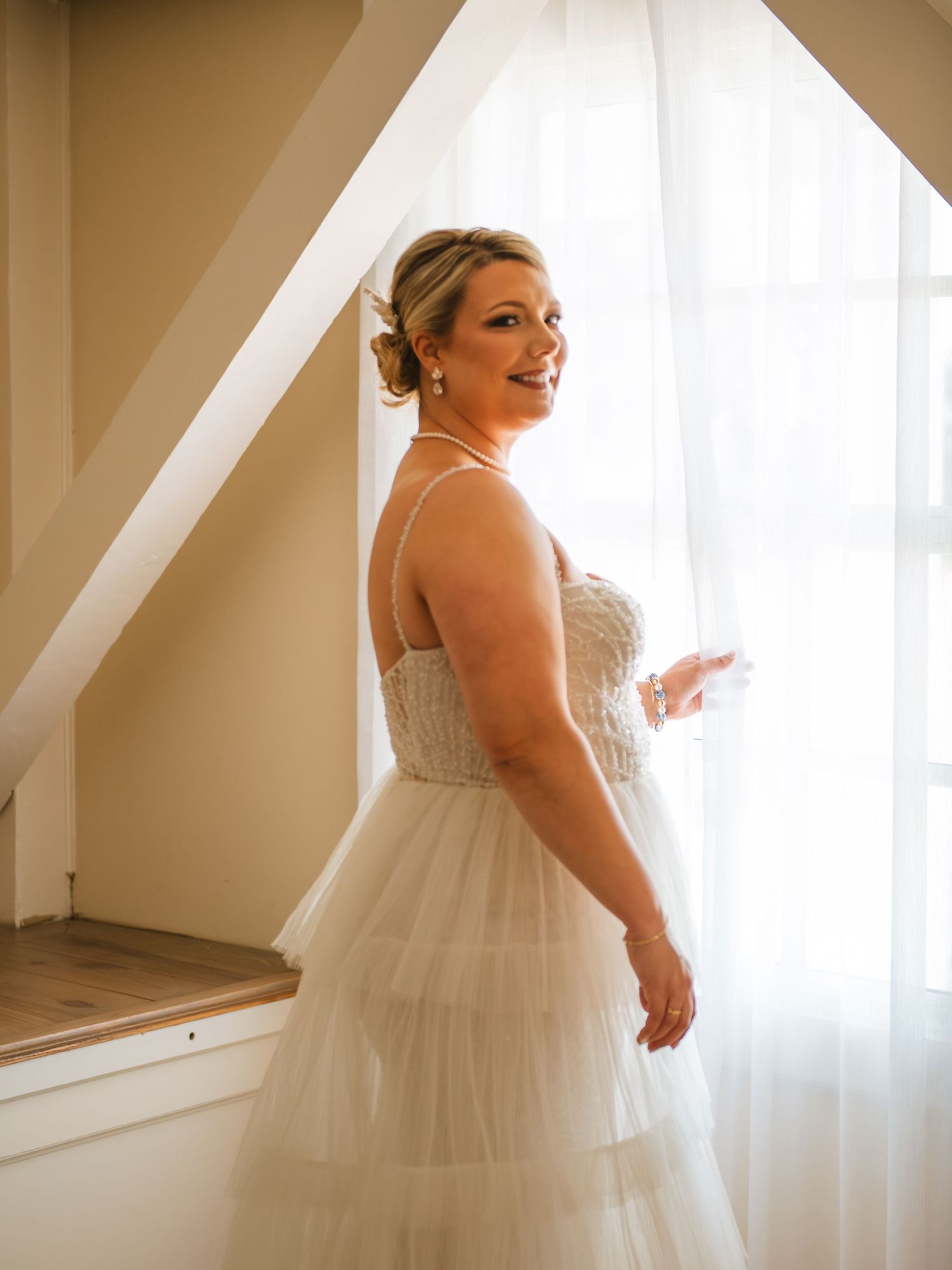 Bride standing by window in soft light during a calm getting ready moment.
At Alhambra Hall Charleston SC