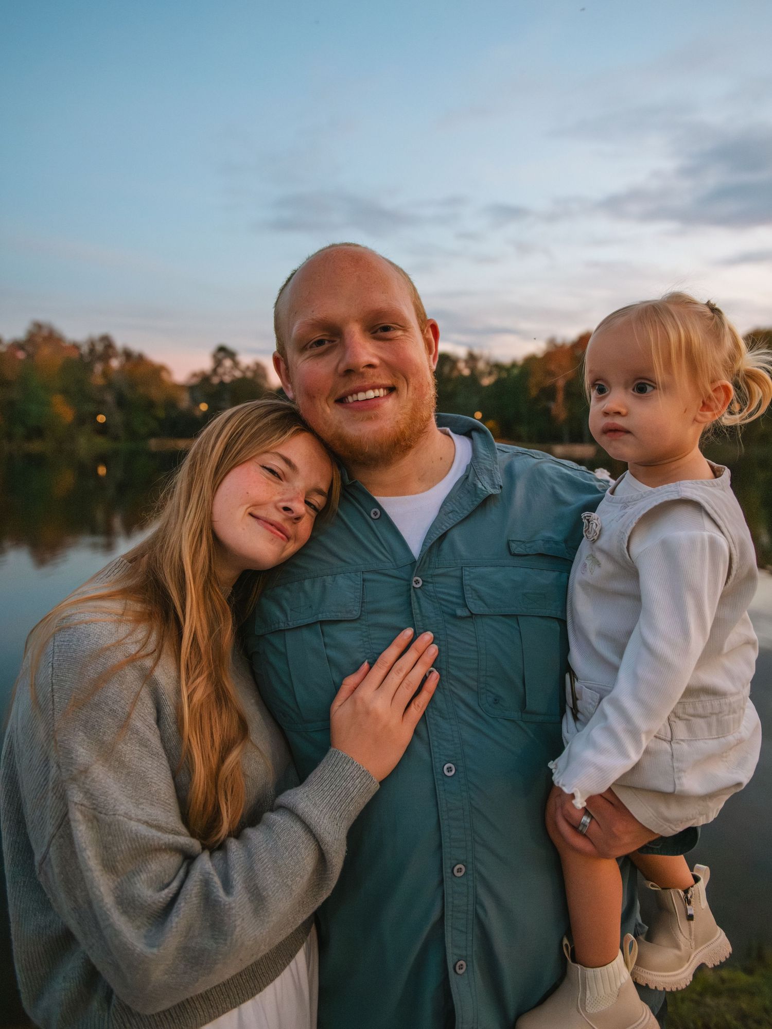 Parents standing close with child in arms during a warm sunset family session by the water.
At the Lexington Old Mill Pond