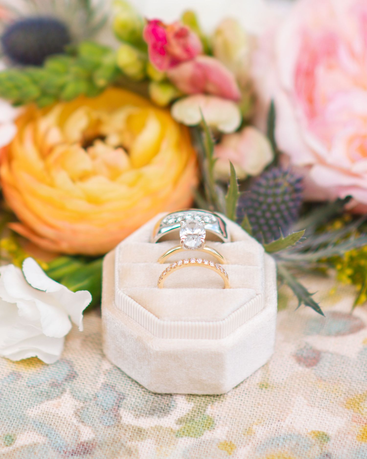 Wedding ring styled with colorful florals during a bright and elegant detail shot.