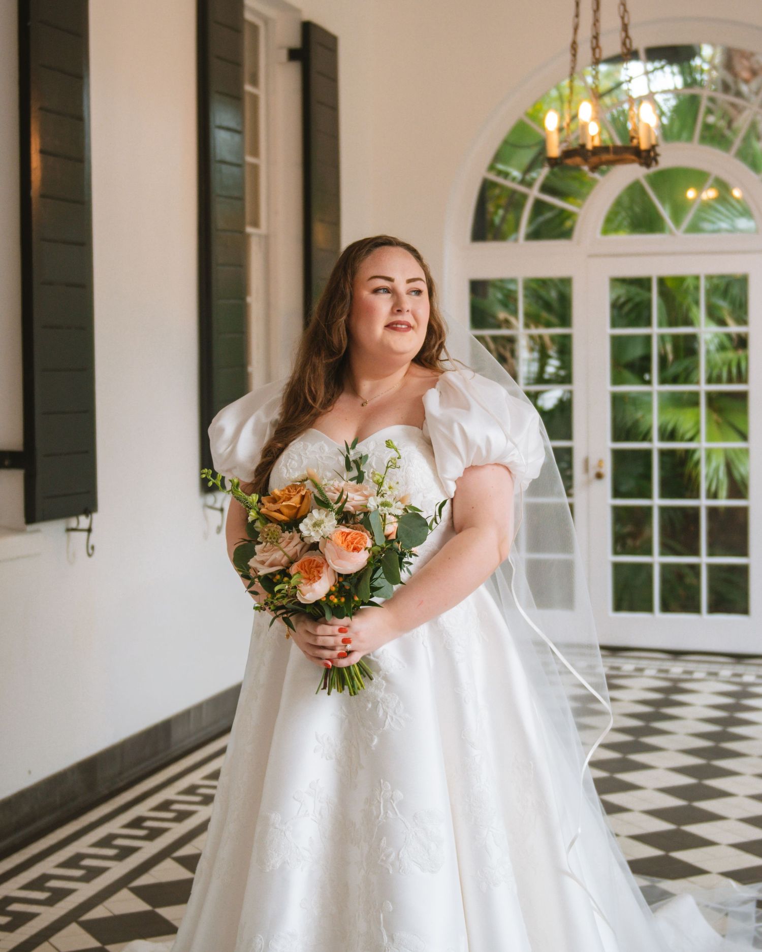 Bride standing indoors holding bouquet during an elegant bridal portrait session At Lowndes Grove Charleston SC