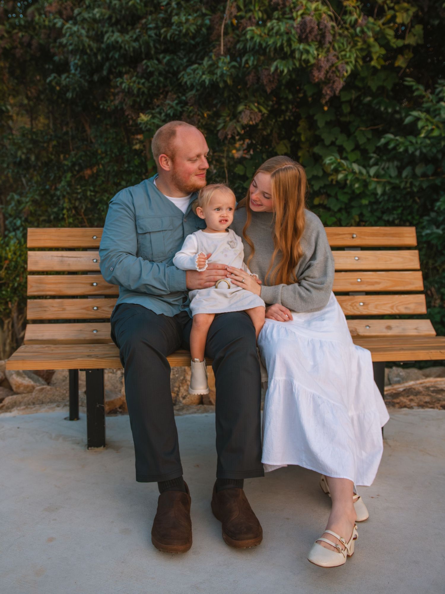 Family sitting together on a bench sharing a sweet moment during an outdoor family session At the Lexington Old Mill Pond