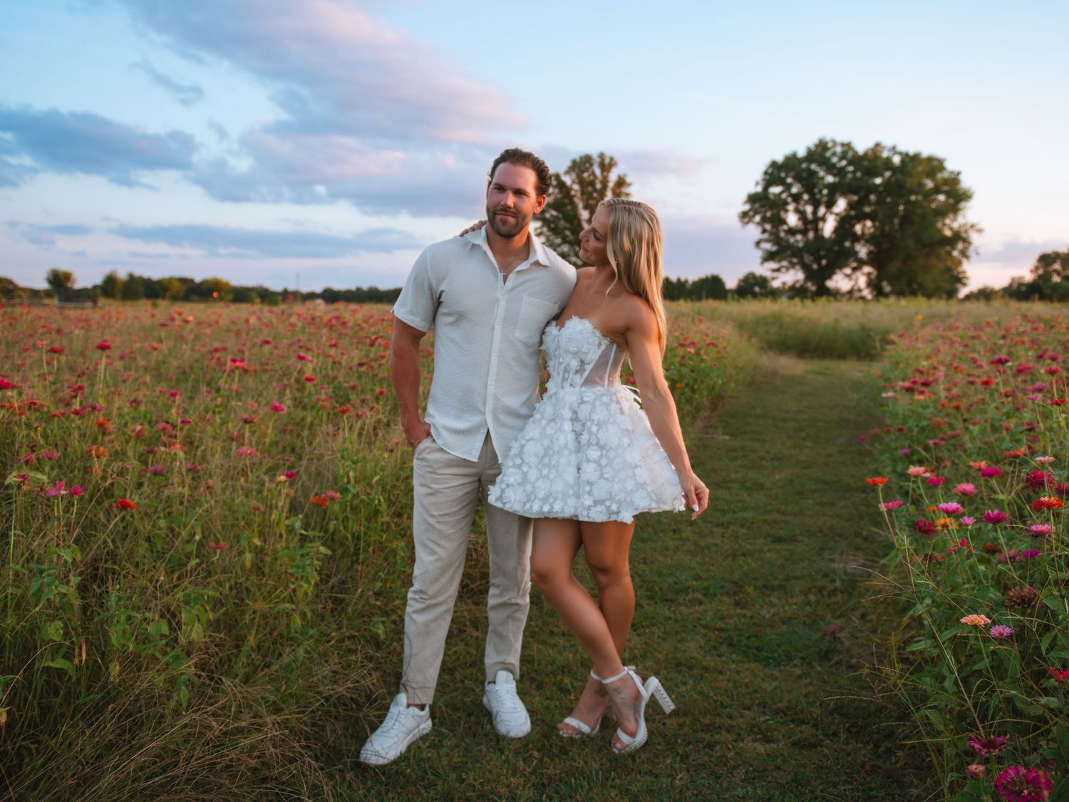 Couple walking together through a flower field during a romantic golden hour session.