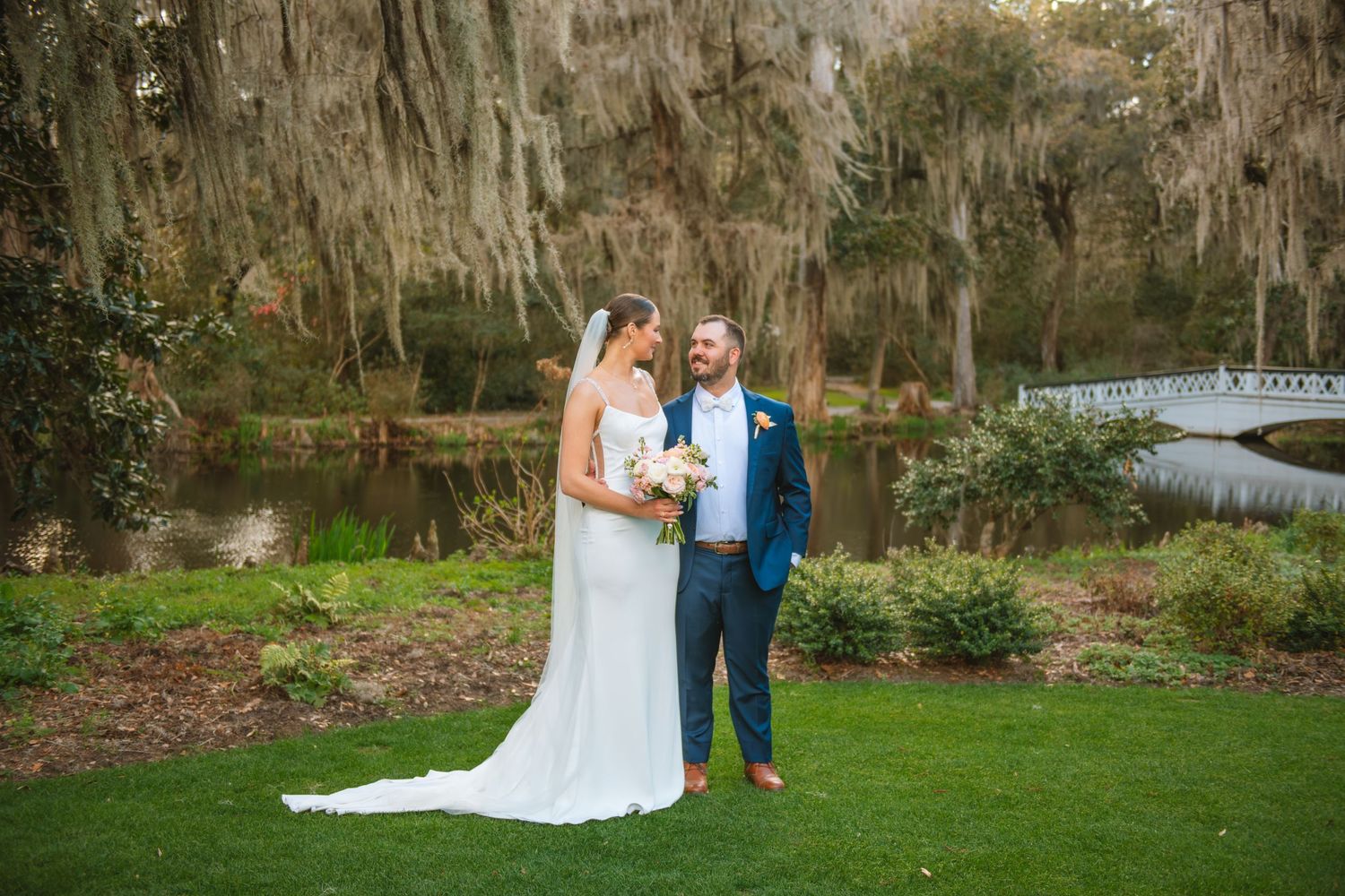 Wedding In Charleston. Bride and groom standing by moss-covered trees during a romantic outdoor wedding portrait in South Carolina.