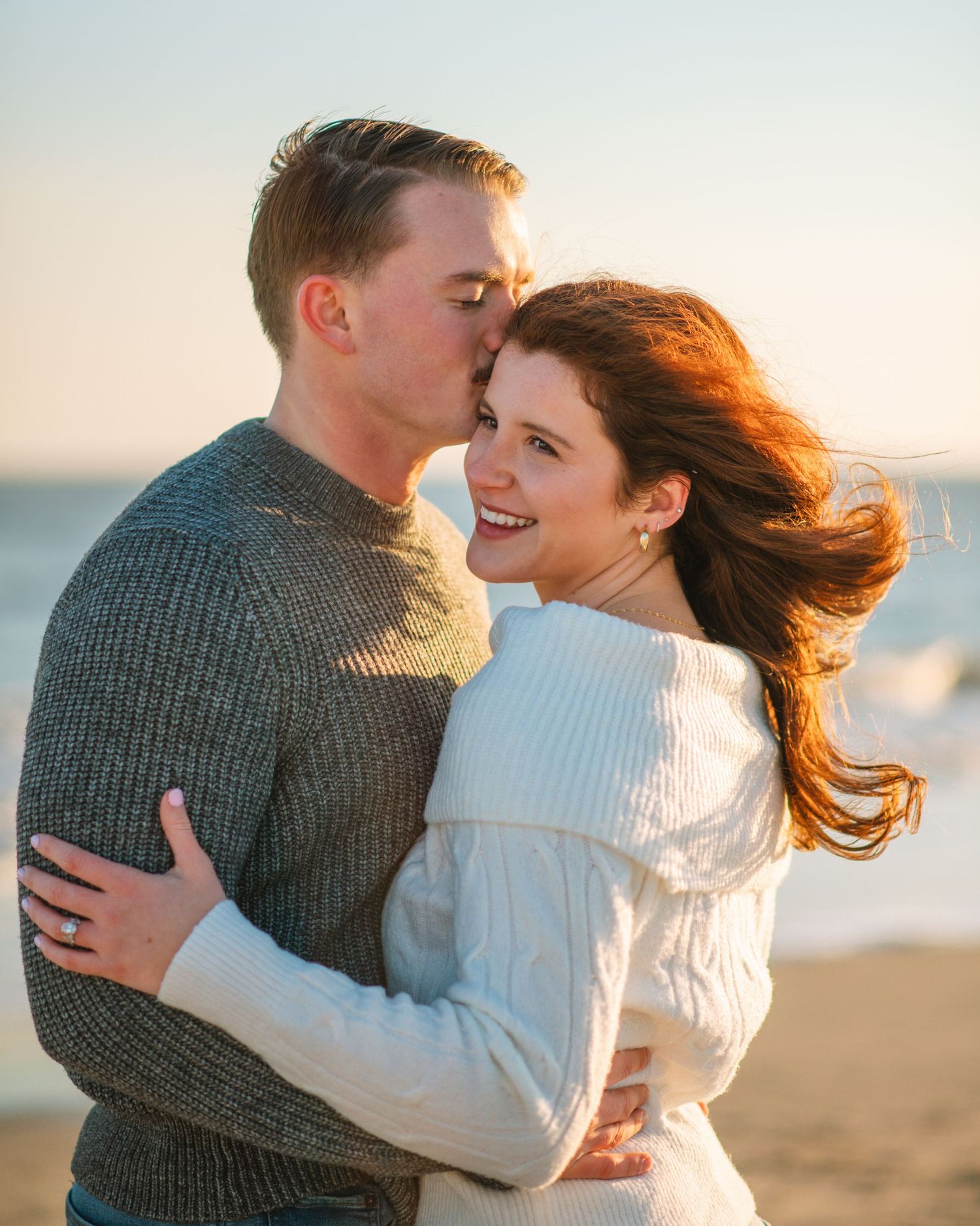 Couple hugging and smiling together during a golden hour beach engagement session.on Sullivans Island, Charleston SC