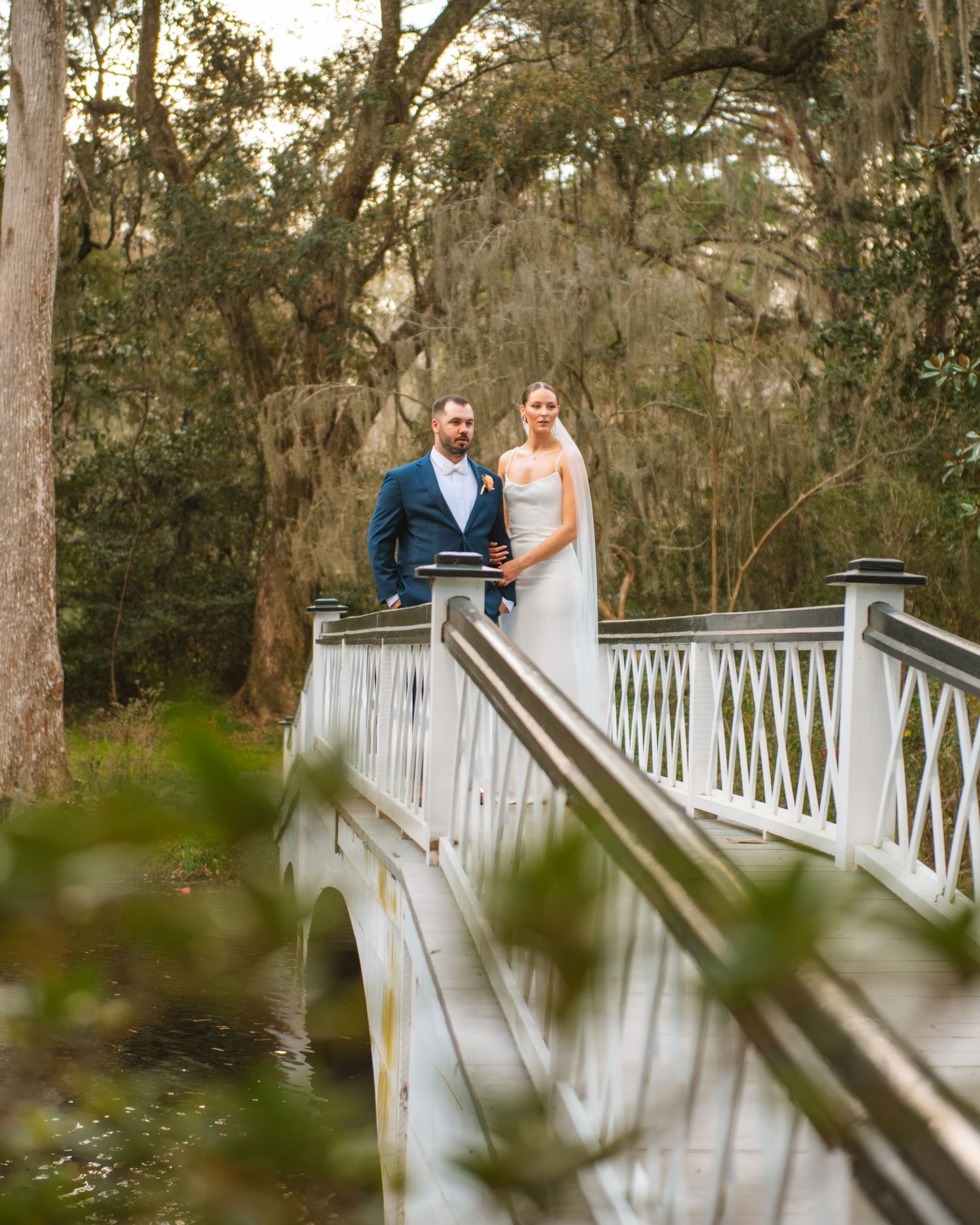 Bride and groom posing on a bridge surrounded by greenery during a South Carolina wedding. Magnolia Plantation and Gardens