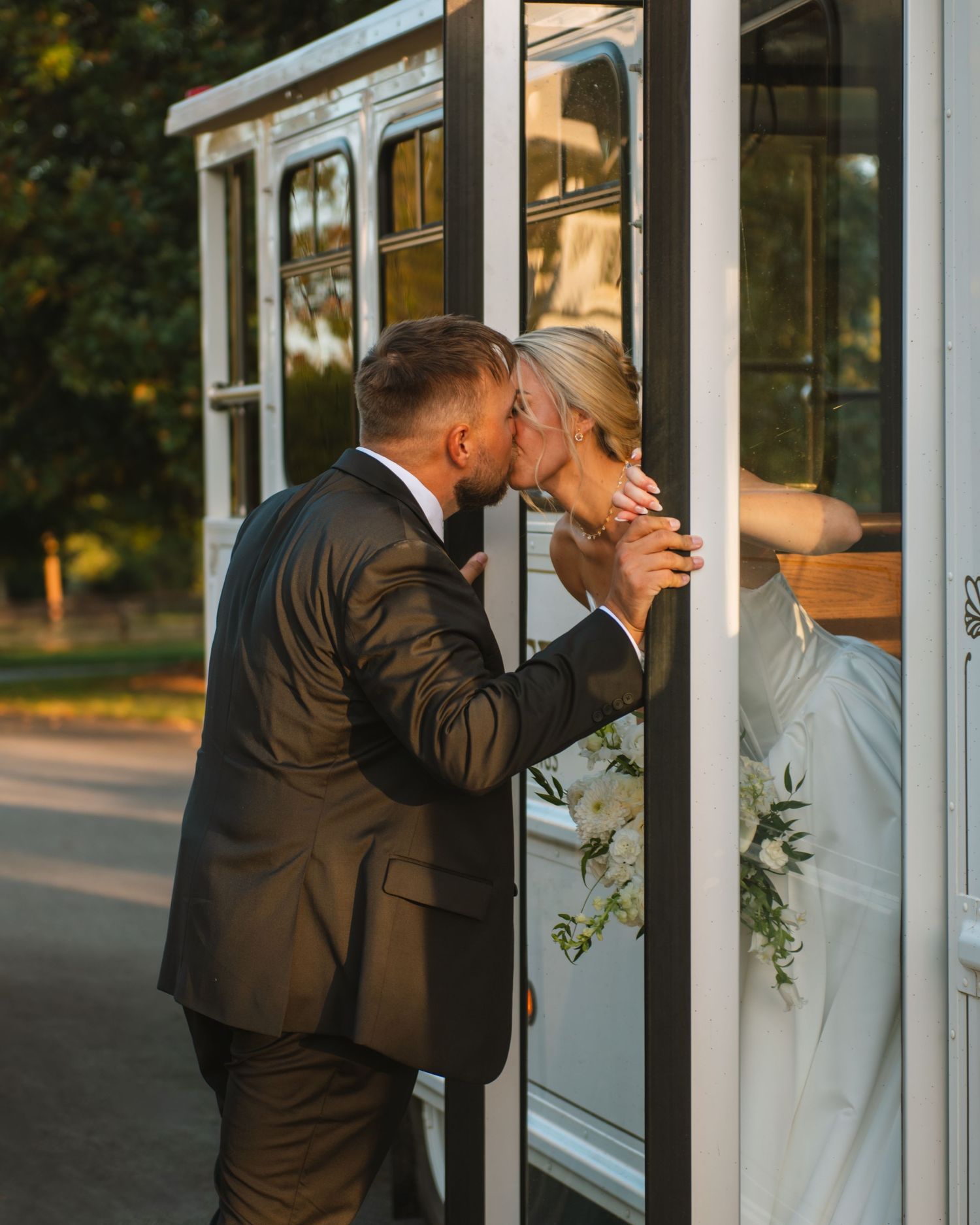 Bride and groom sharing a kiss through a glass door during a romantic wedding moment.