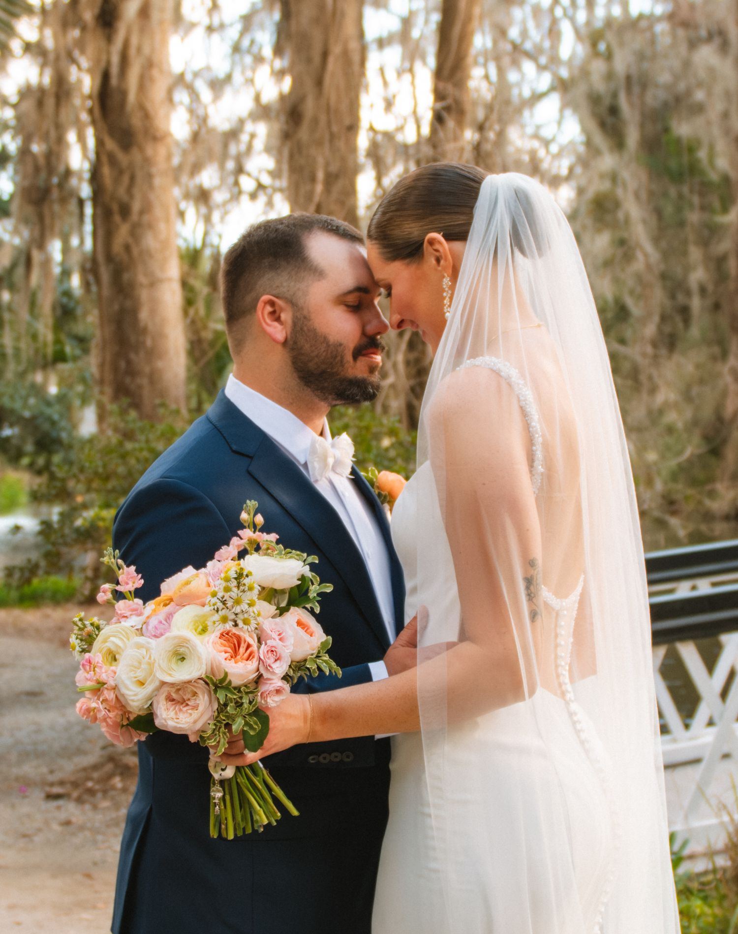Bride and groom standing together under mossy trees during a romantic outdoor wedding portrait. Magnolia Plantation and Gardens