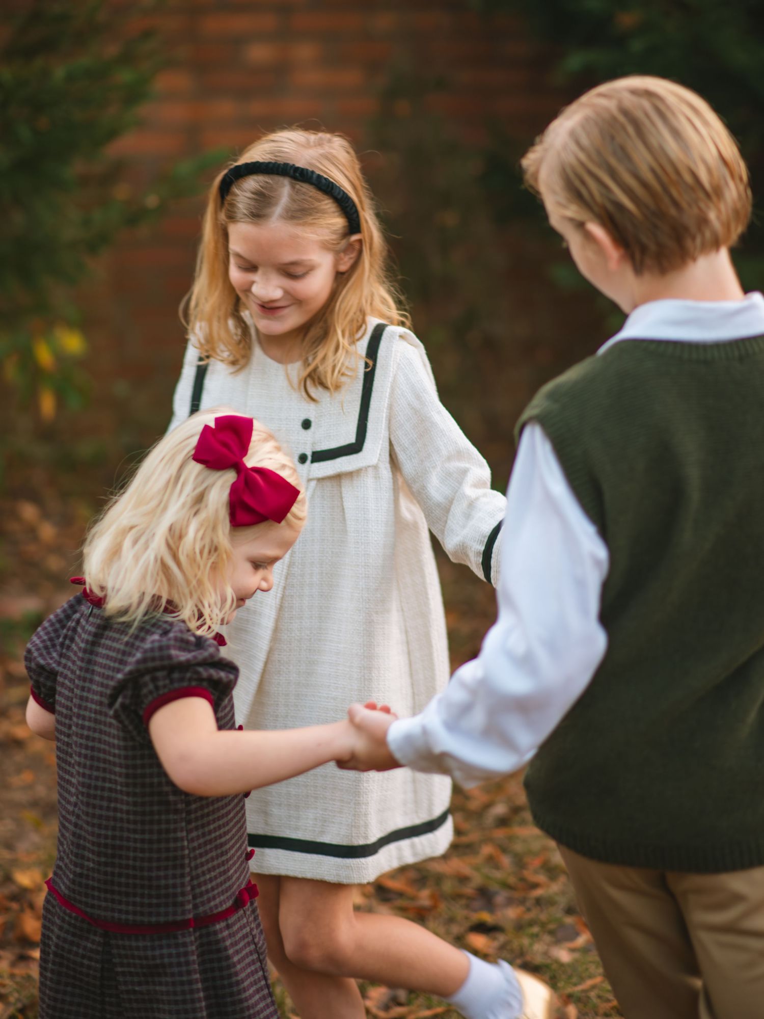 Children holding hands and playing together during a joyful outdoor fall family photography session.