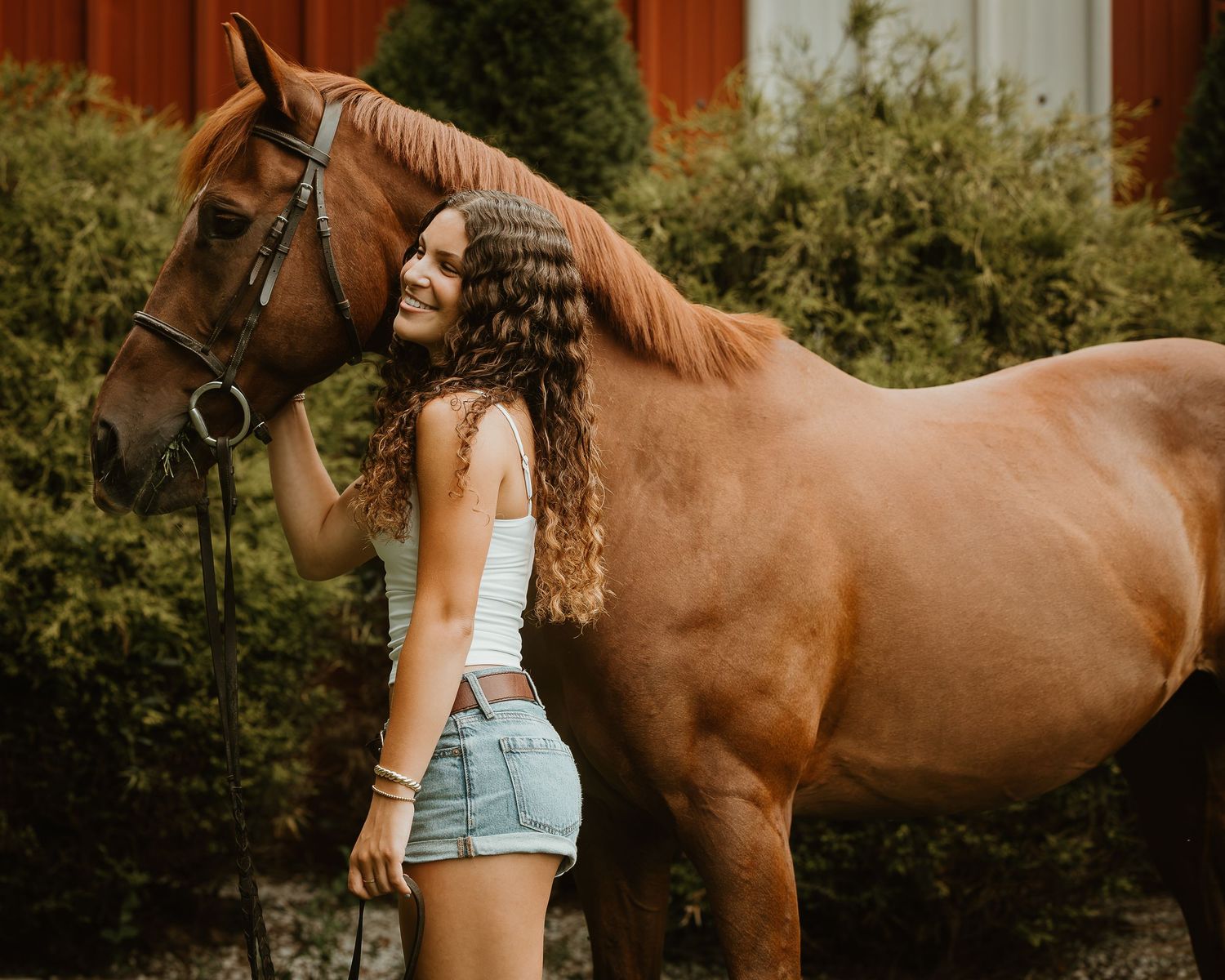Young rider standing beside her chestnut horse during an equestrian photography session in Connecticut.