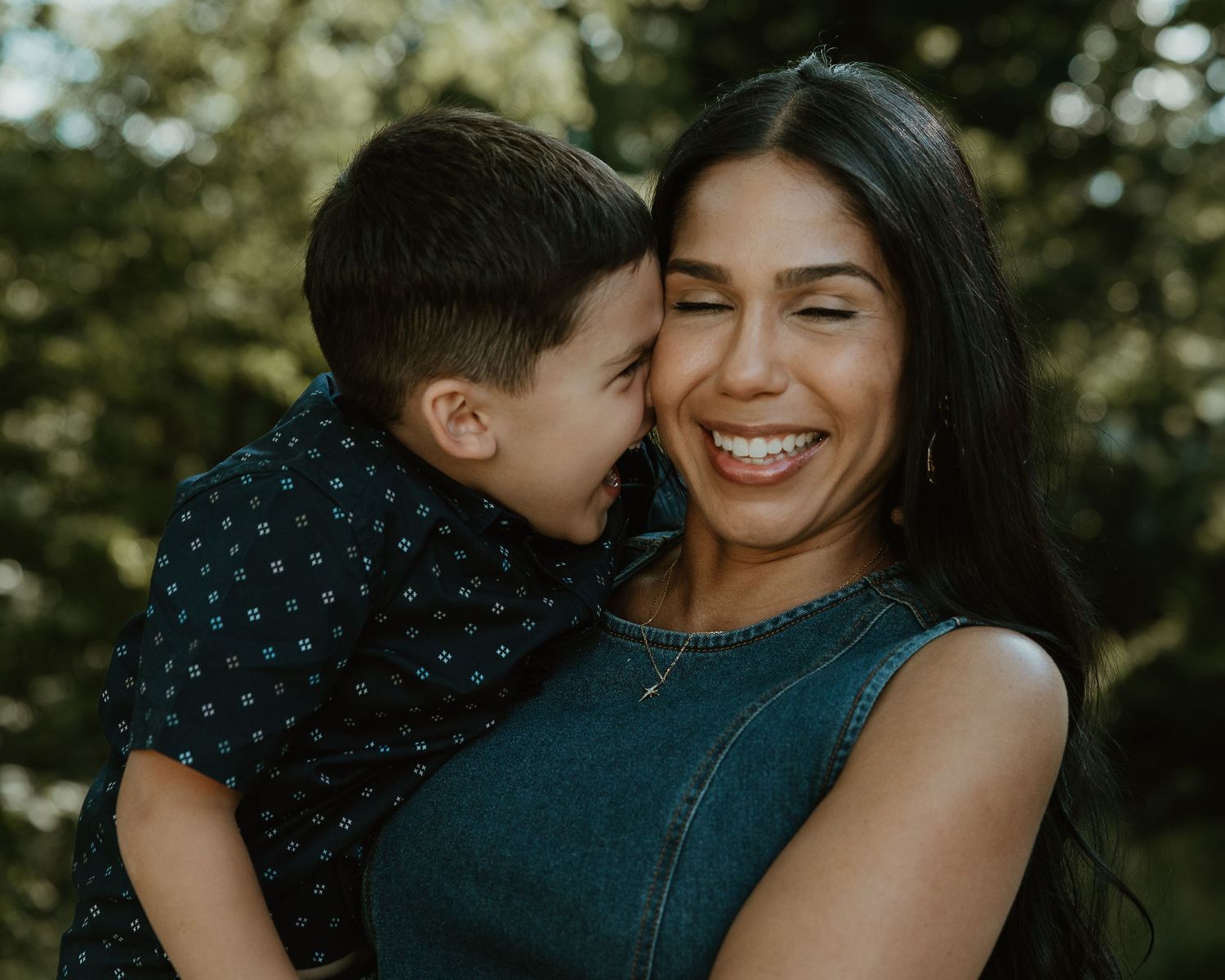Young boy whispering to his laughing mother during an outdoor portrait session, New Haven County CT