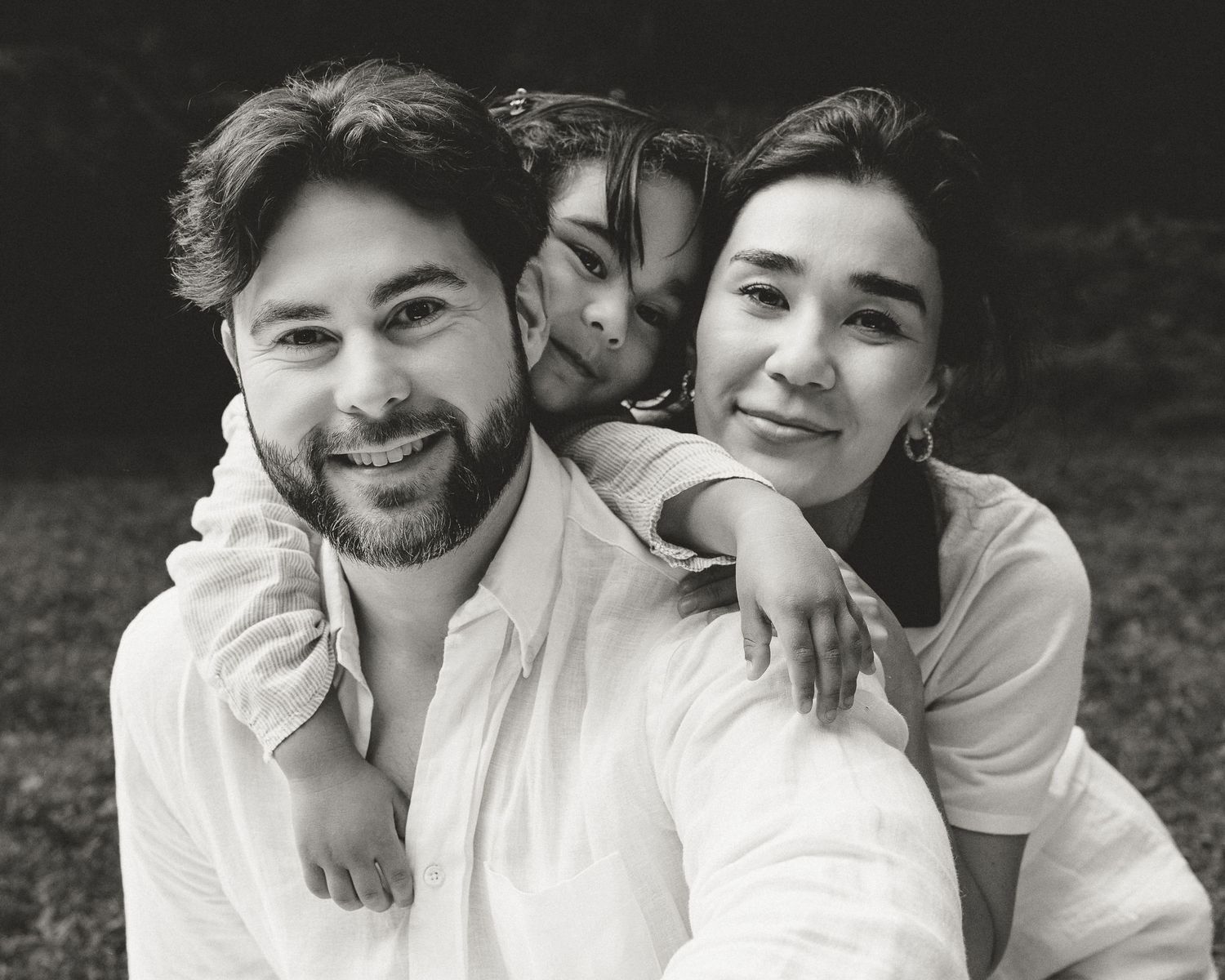Parents smiling together with their young son during an outdoor family portrait session in Woodbridge, Connecticut.