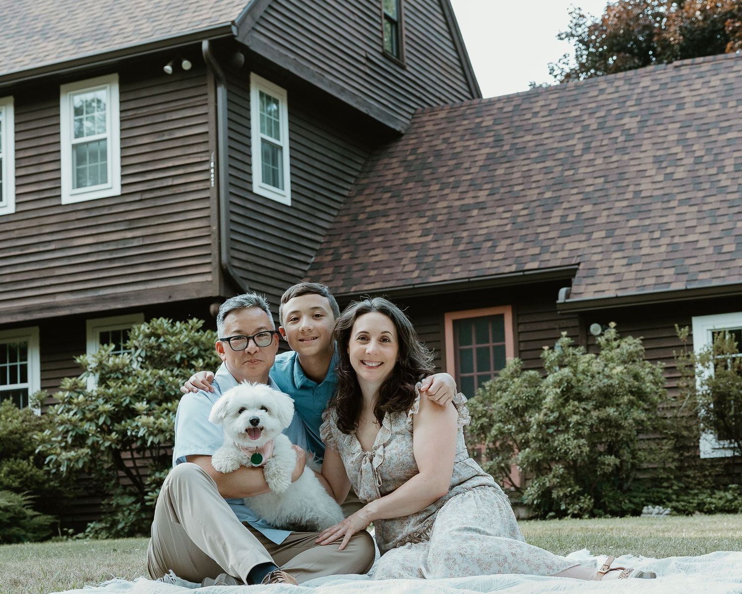 Family portrait photographer in Woodbridge CT capturing a mother, father, son, and their dog together outdoors