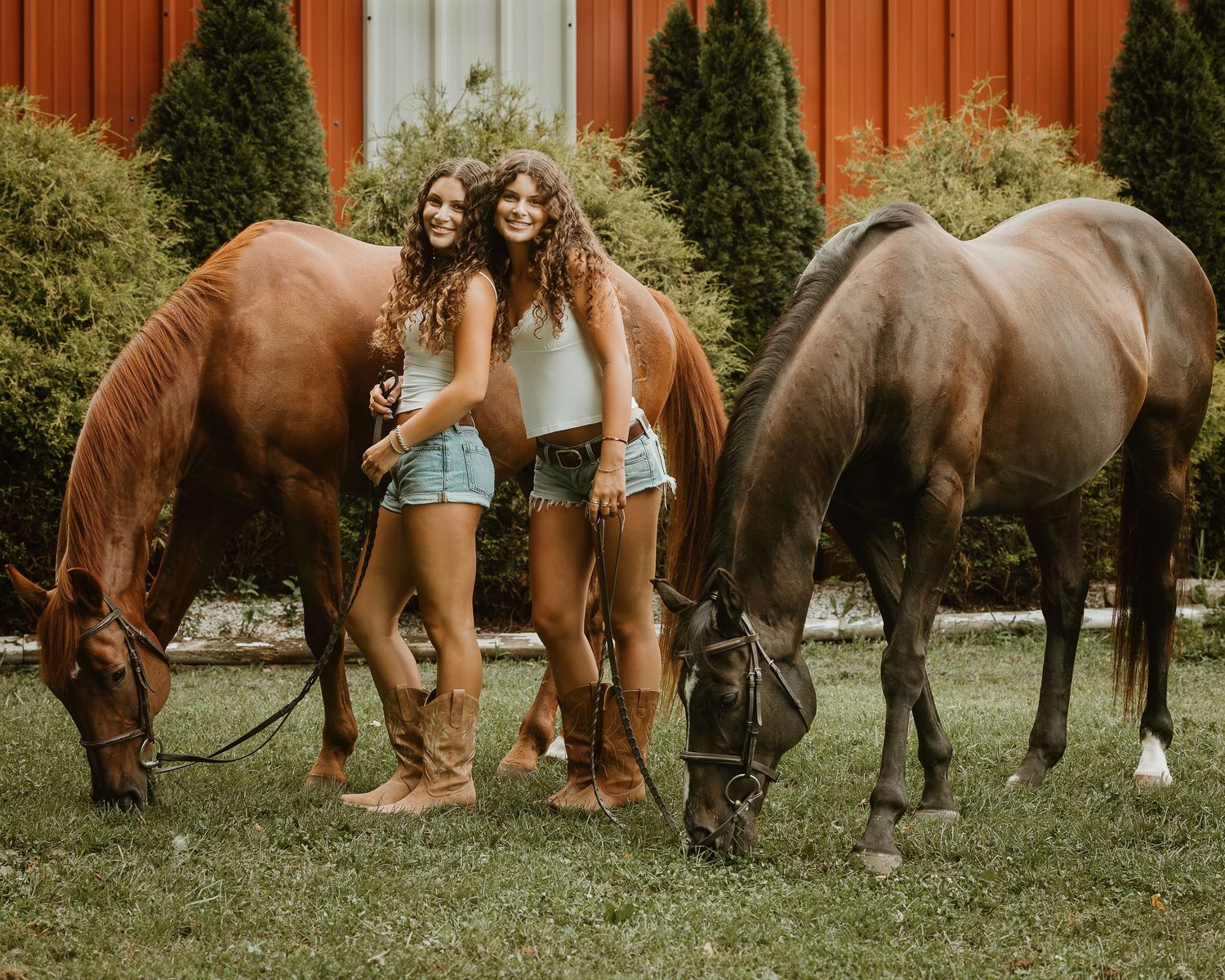 Twin high school seniors posing with two horses during an equestrian senior portrait session in Connecticut