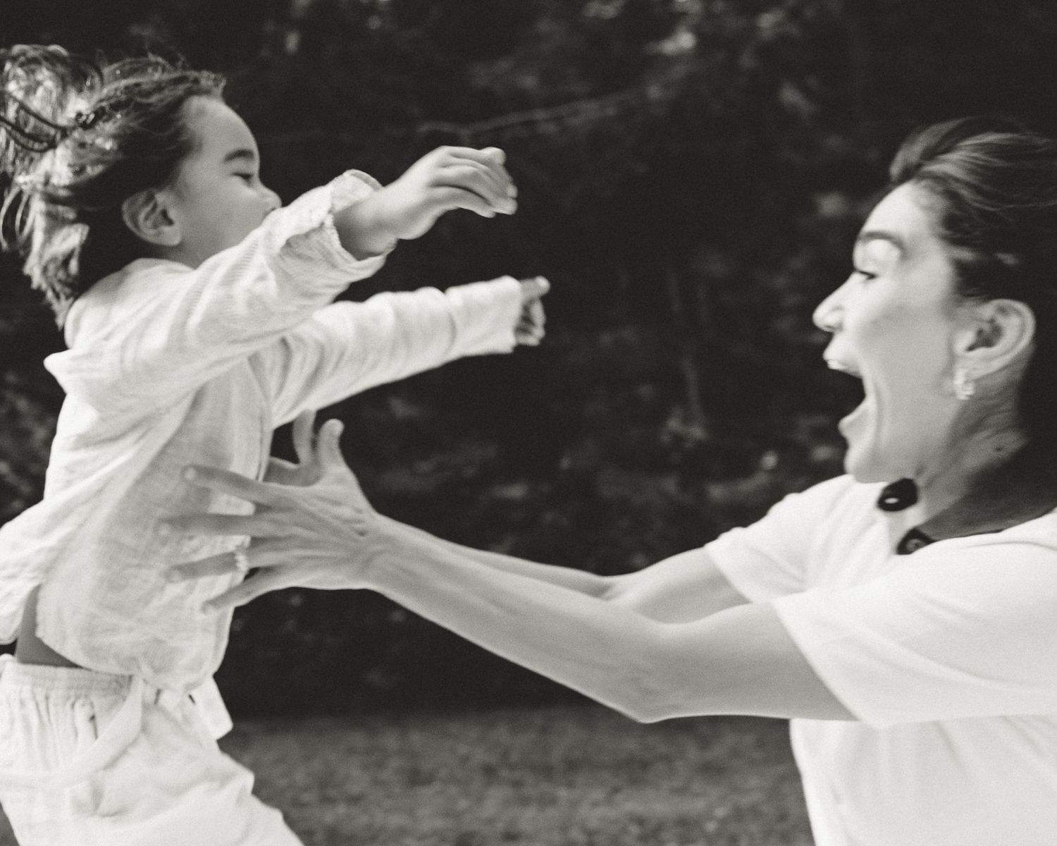 Mother reaching toward her laughing young son during a playful outdoor family portrait session in Connecticut.
