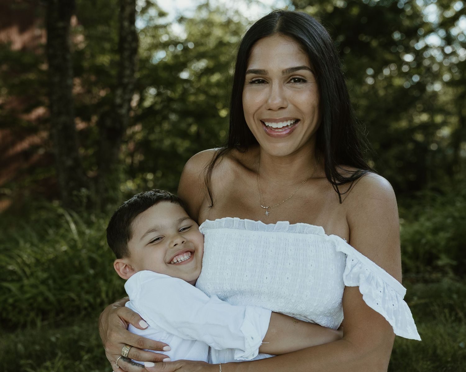 Mother laughing while holding her son in white outfits, family photographer Woodbridge CT