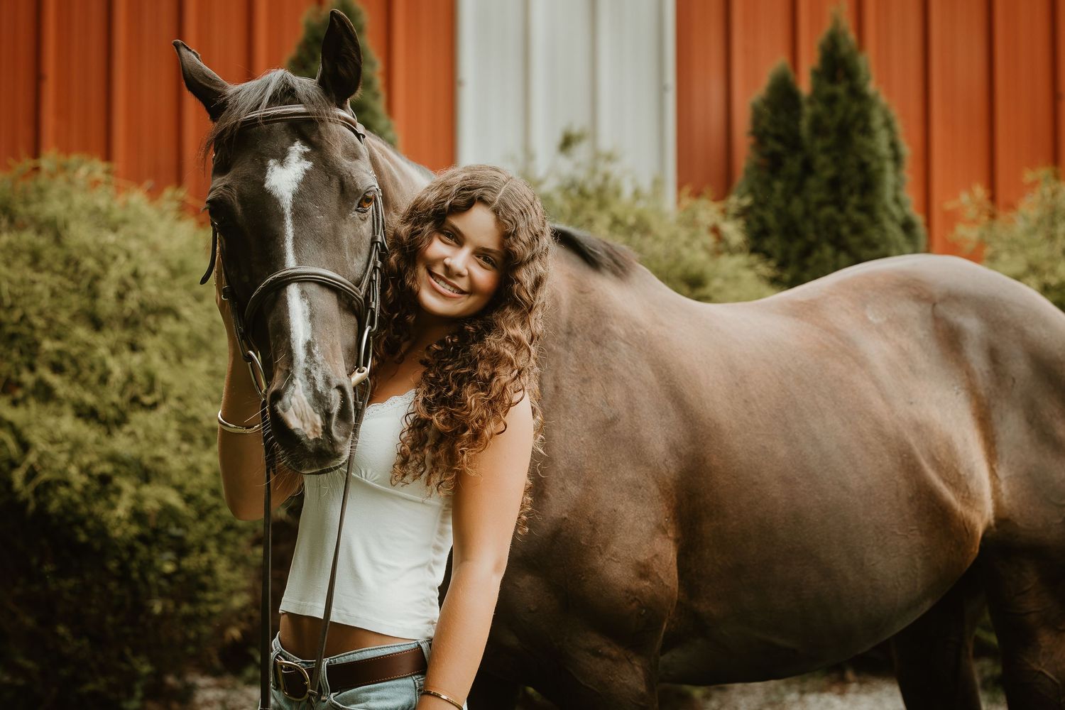 Young equestrian smiling beside her horse during a Connecticut equestrian portrait session.