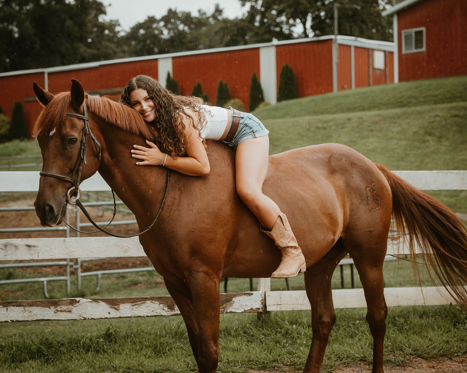 High school senior lying across her chestnut horse during a relaxed equestrian portrait session in Connecticut
