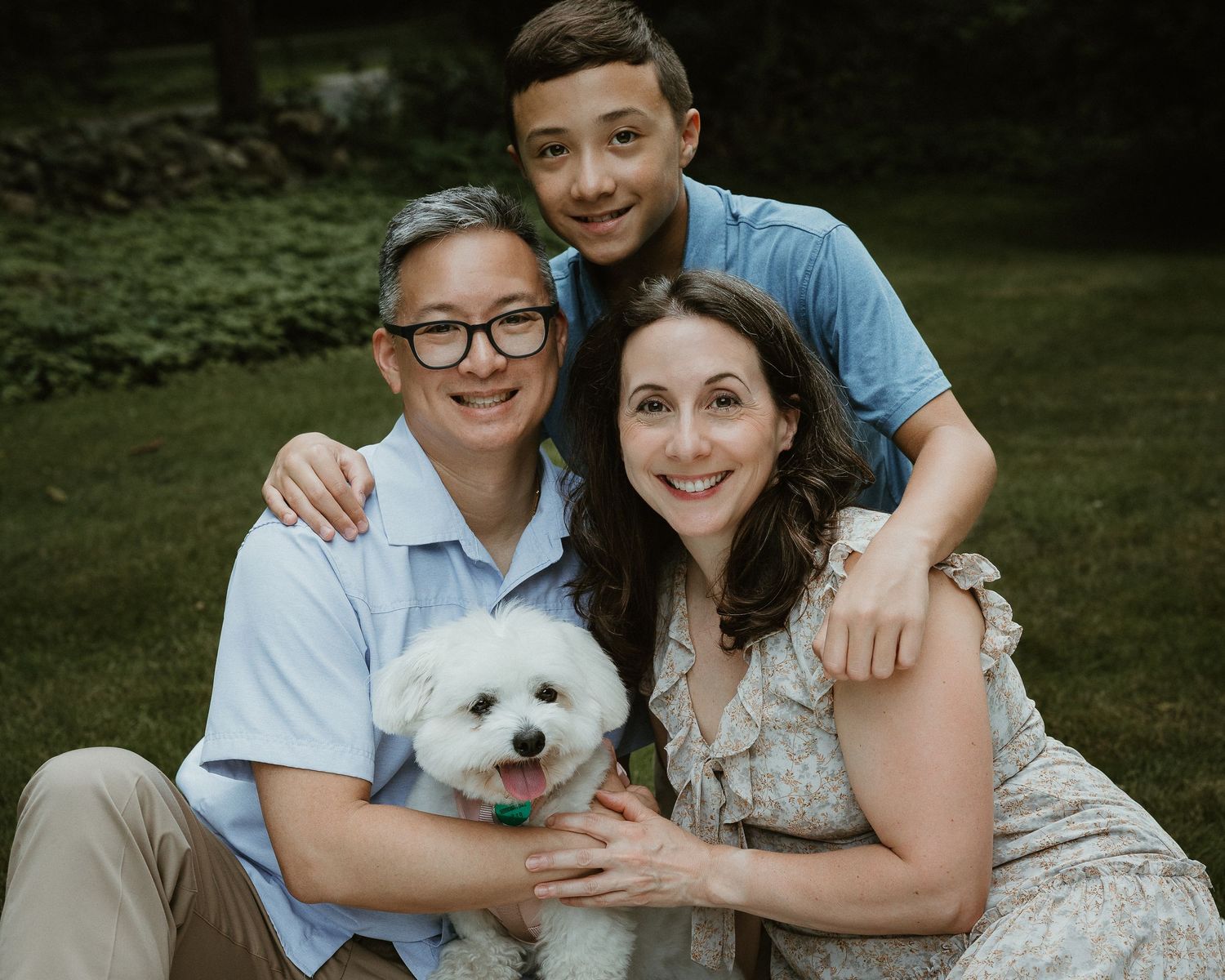 Outdoor family portrait in Woodbridge CT of parents and their son seated together with their dog