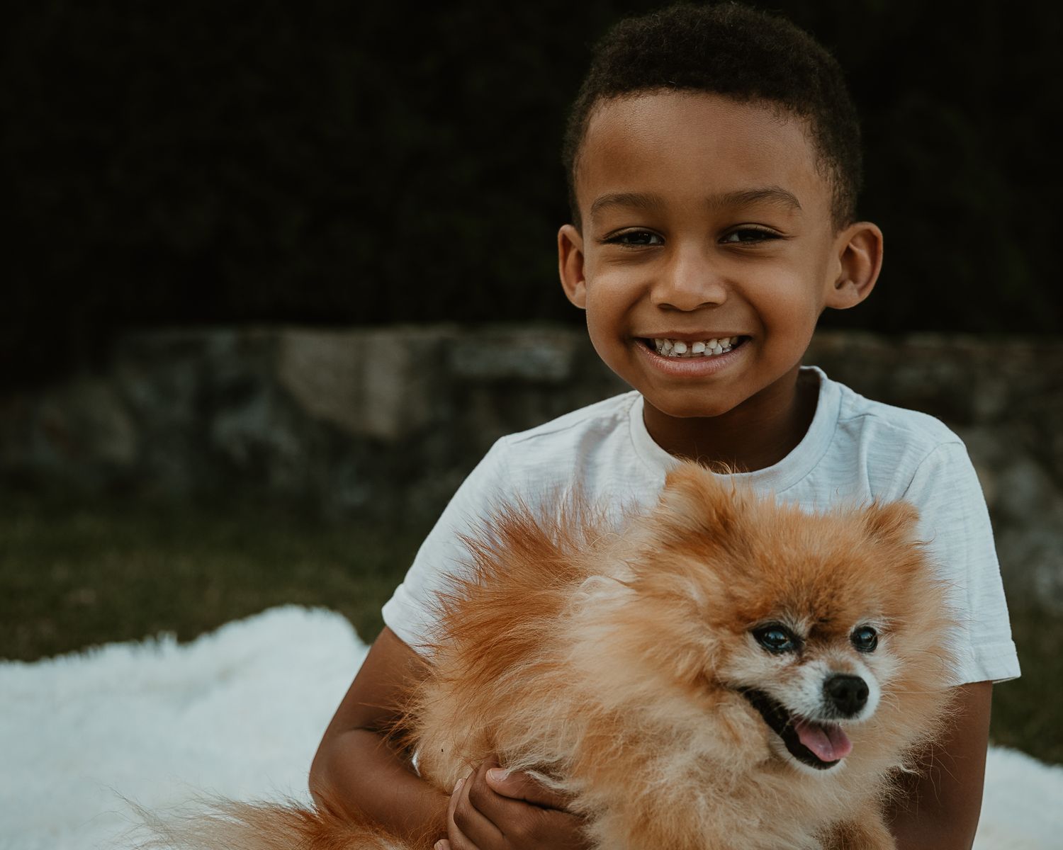 Smiling boy holding the family's Pomeranian outdoors, Connecticut family photography session