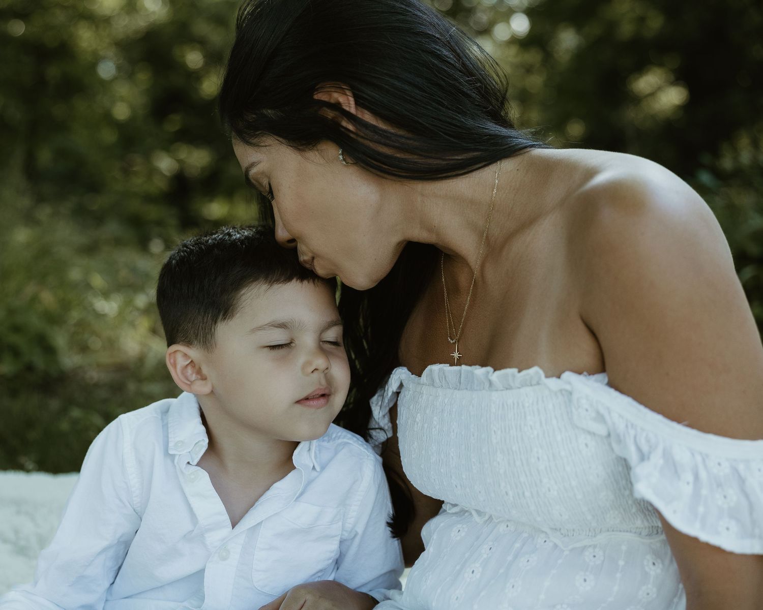 Mother kissing her son's forehead in white outfits outdoors, family photographer Woodbridge Connecticut