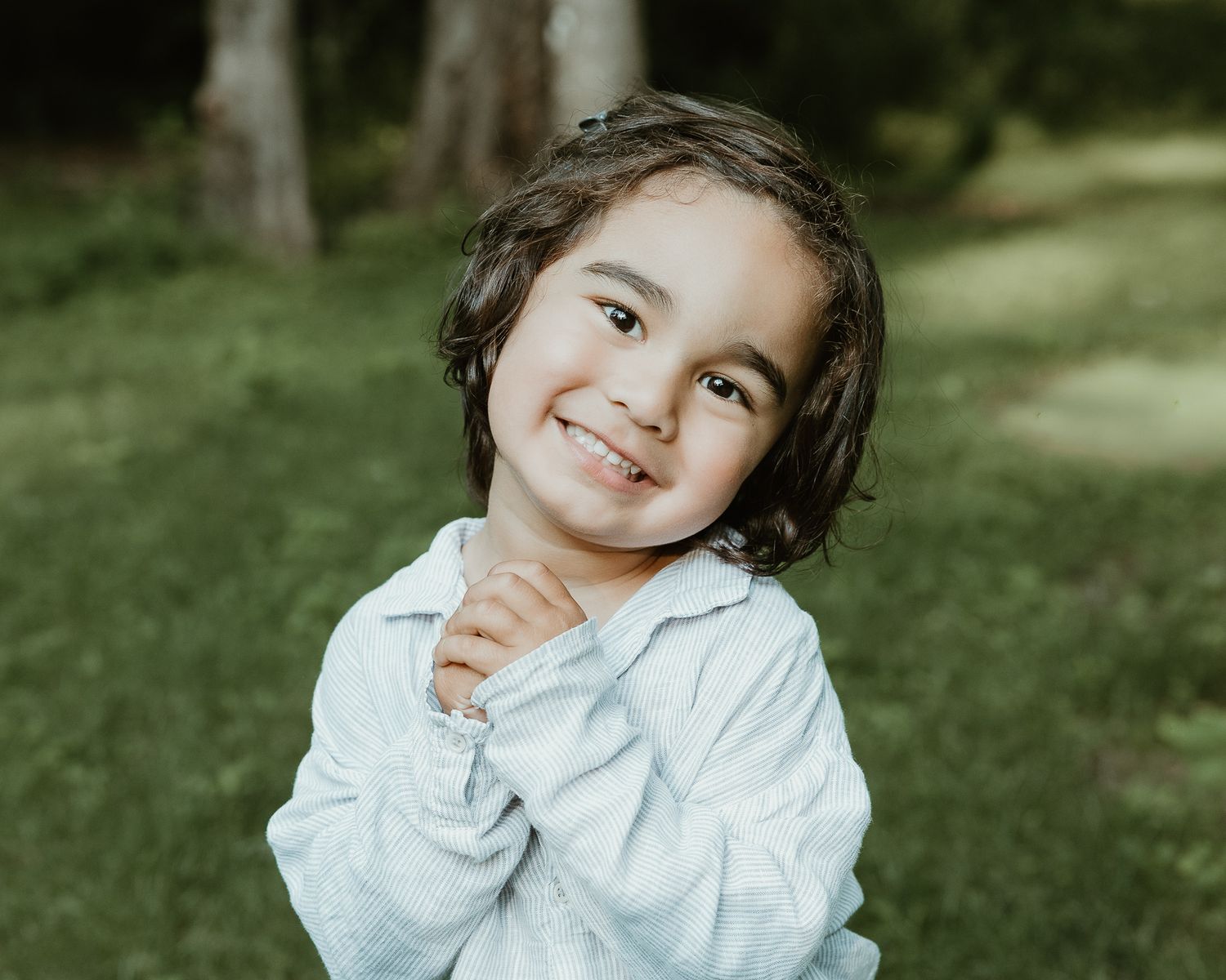 Young child smiling outdoors in a wooded setting, Woodbridge, CT family photography