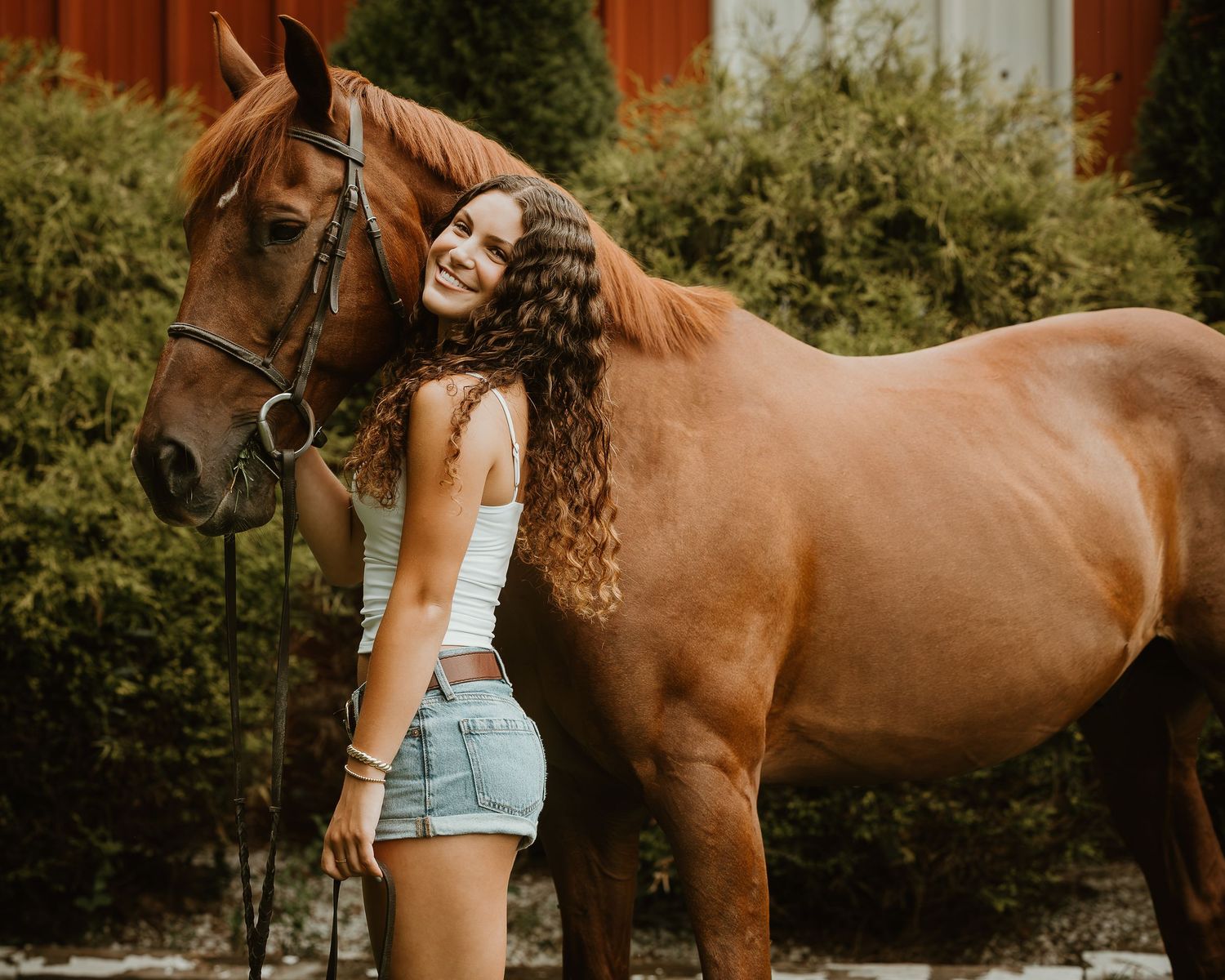 High school senior standing beside her chestnut horse during an outdoor equestrian portrait session in Connecticut