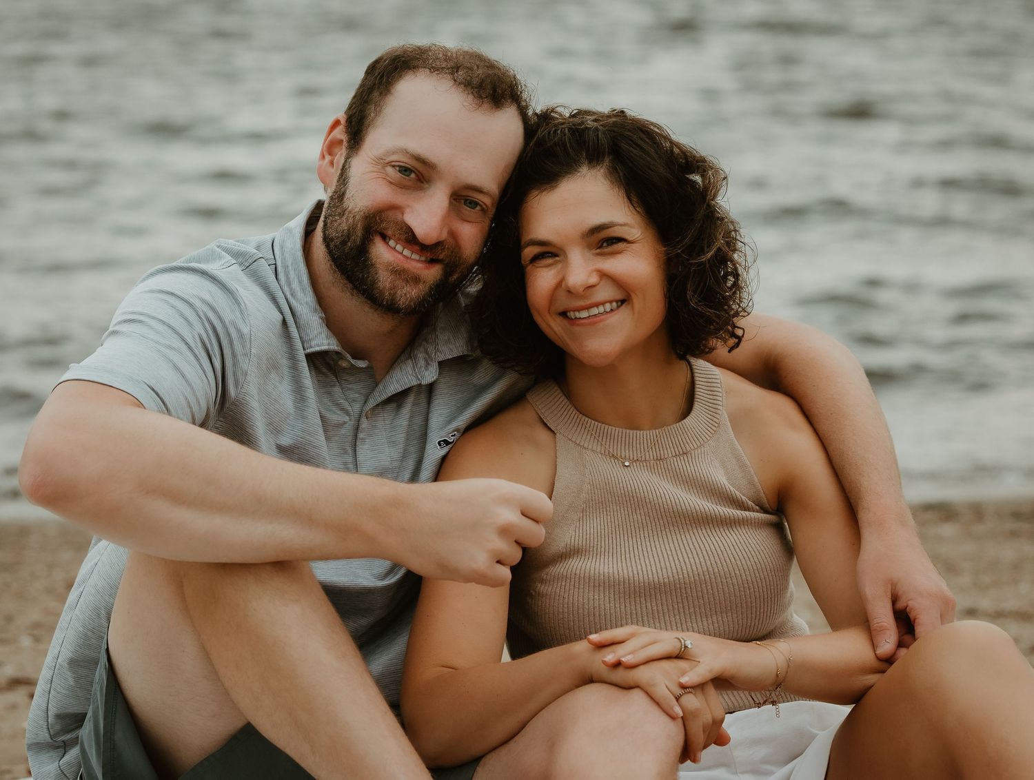 Couple sitting together by the water during a family portrait session at Branford Point in Connecticut