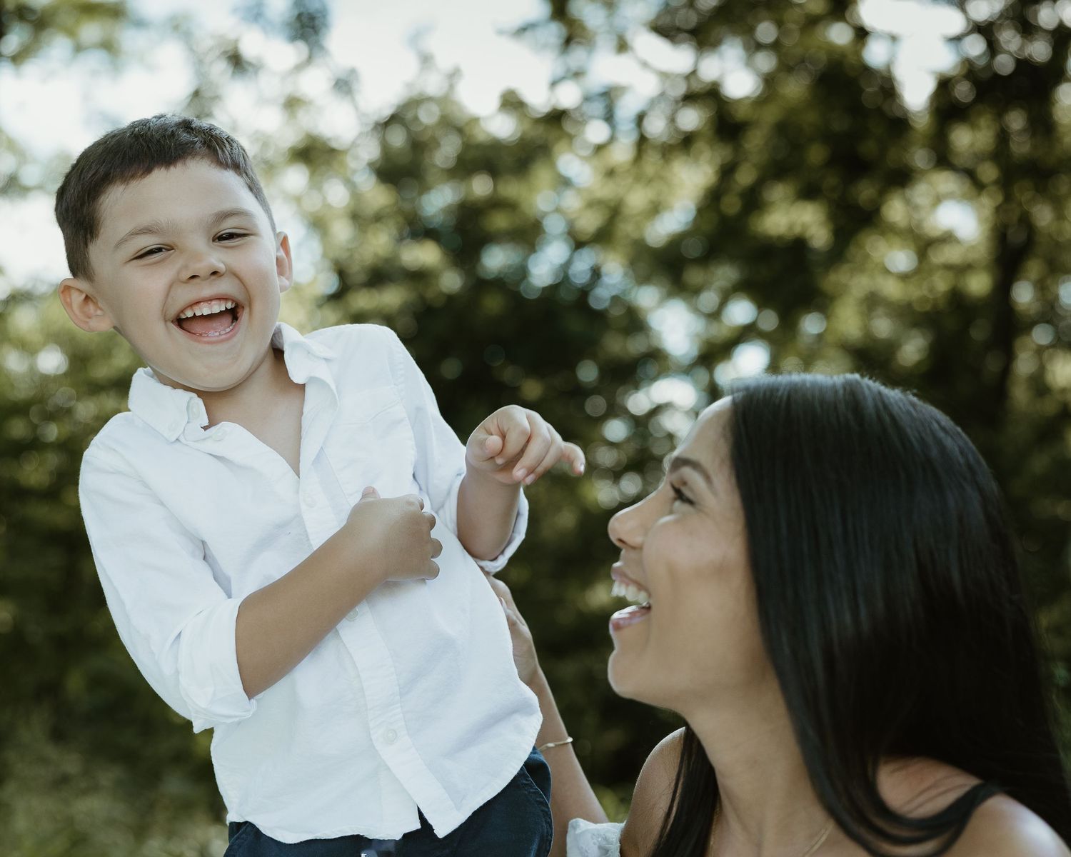 Mother laughing with her son in white outfits outdoors, family photographer Woodbridge CT