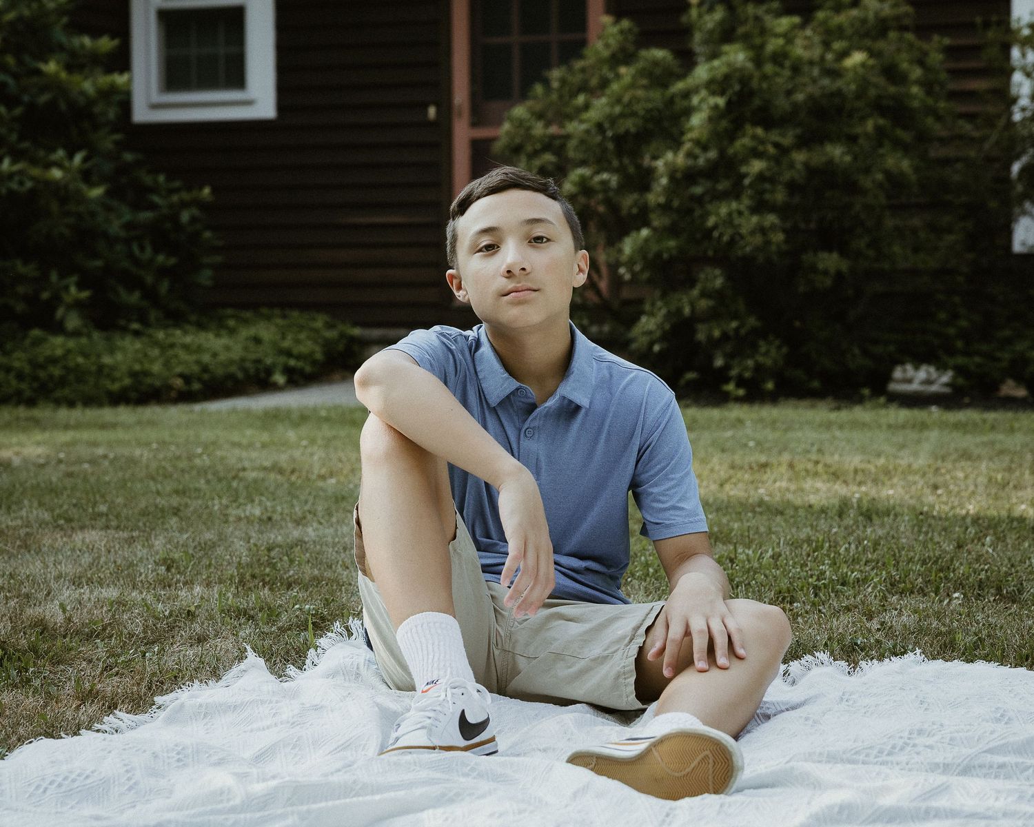 Teenage boy sitting on a blanket in the front yard during a family portrait session in Woodbridge, CT