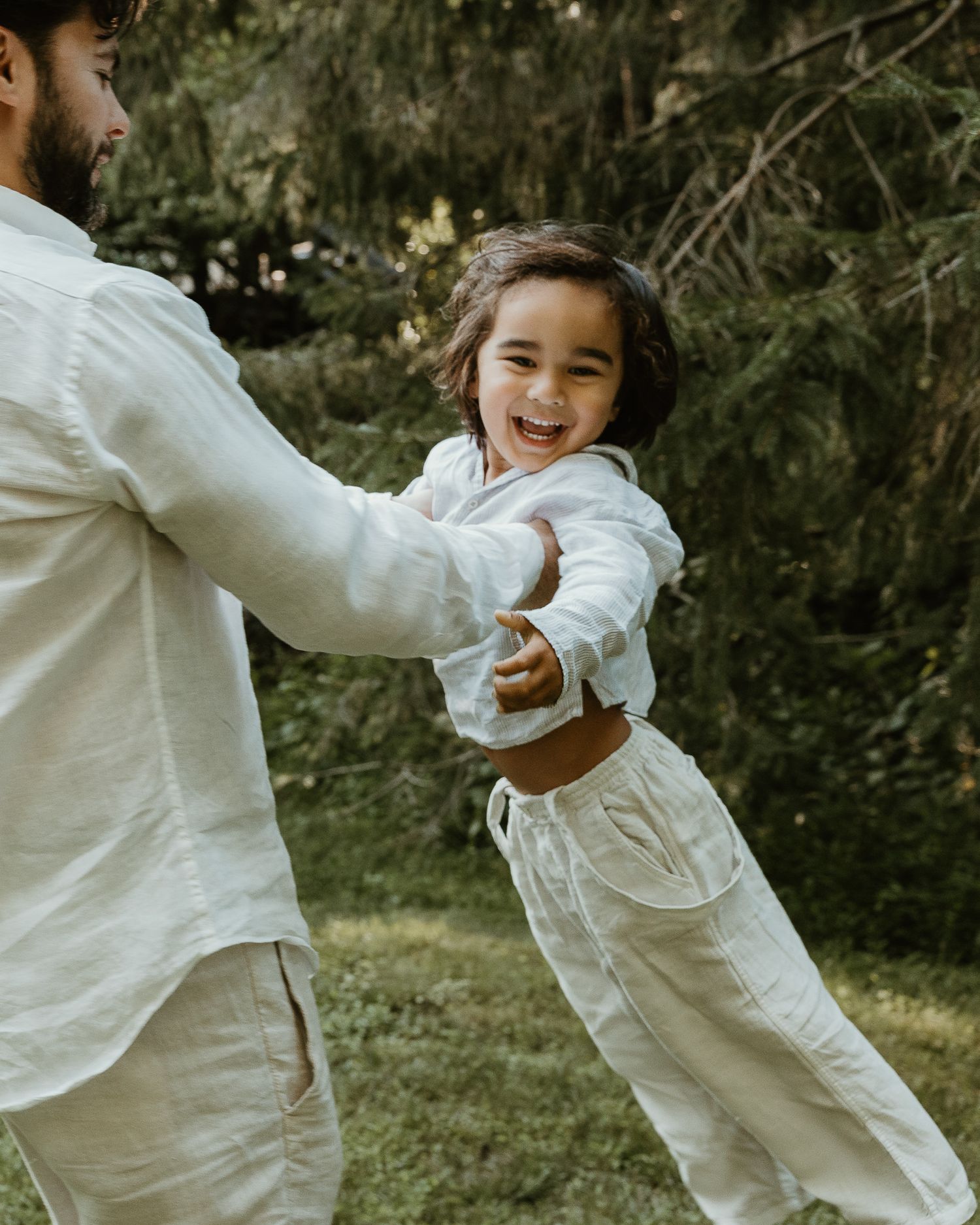Father swinging young child playfully outdoors, candid family portrait in Woodbridge, CT