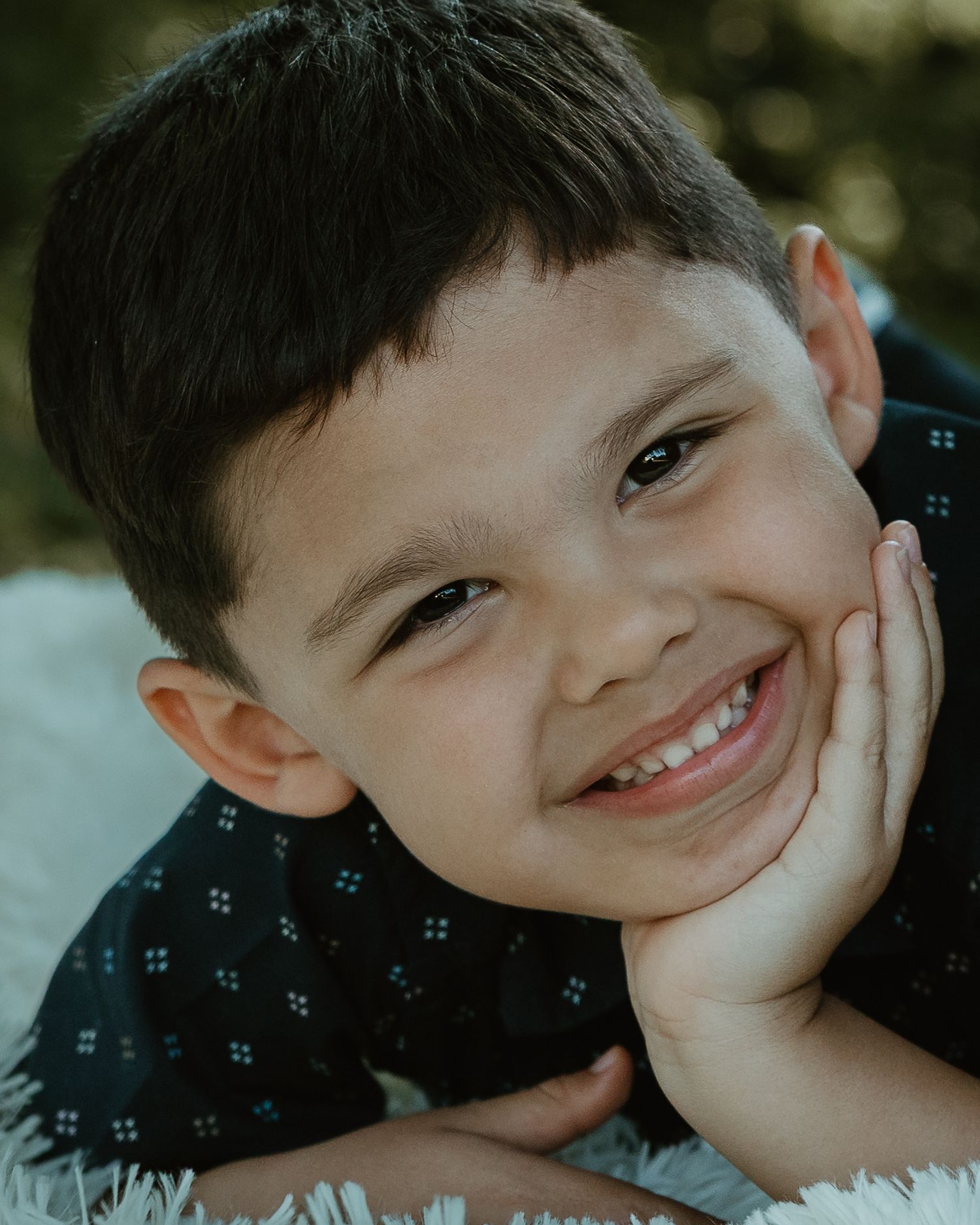 Young boy resting his chin on his hand, smiling outdoors, child portrait New Haven County CT