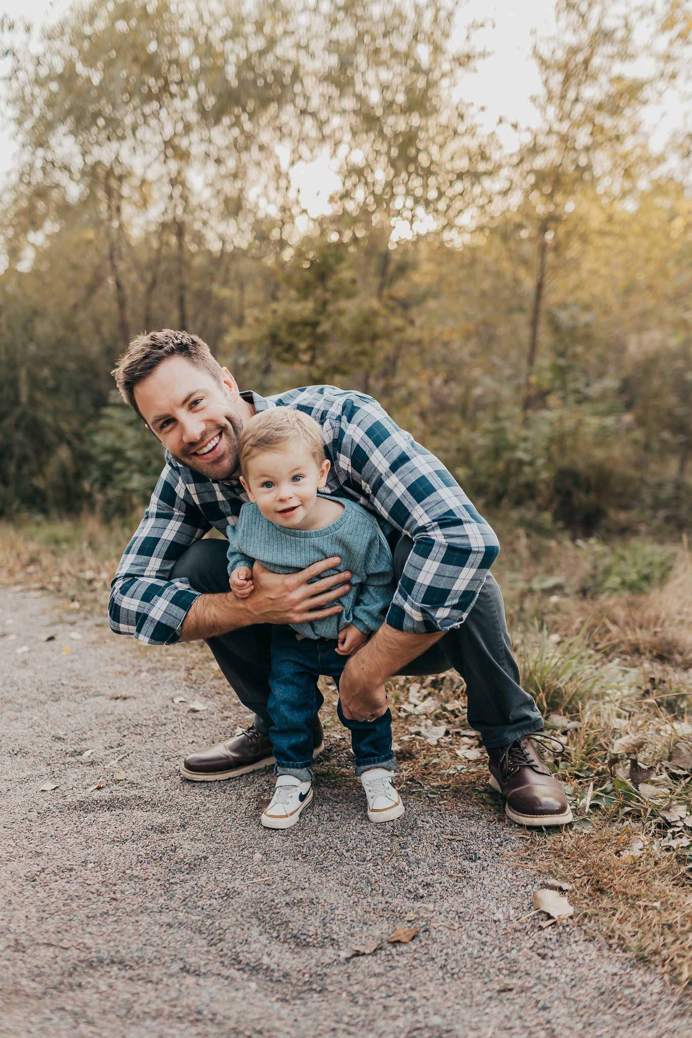 A heartwarming outdoor portrait of a parent and child sharing a playful moment on a path.