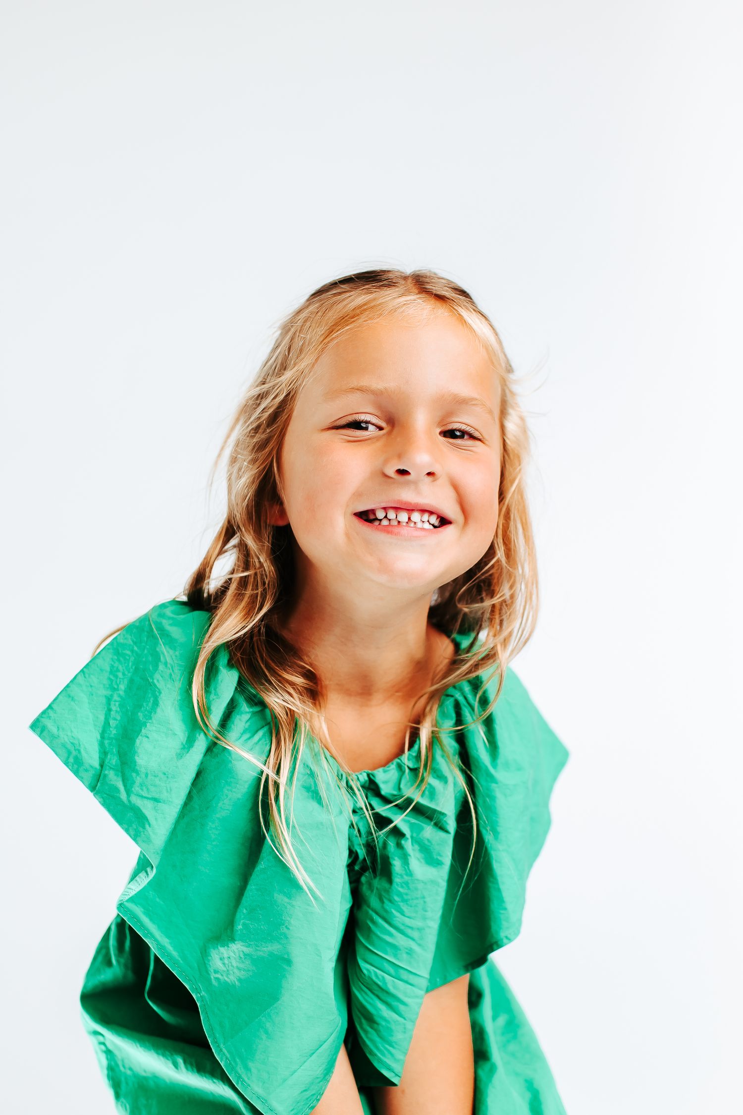 Dynamic poses in an emerald green ruffled top against white background.
