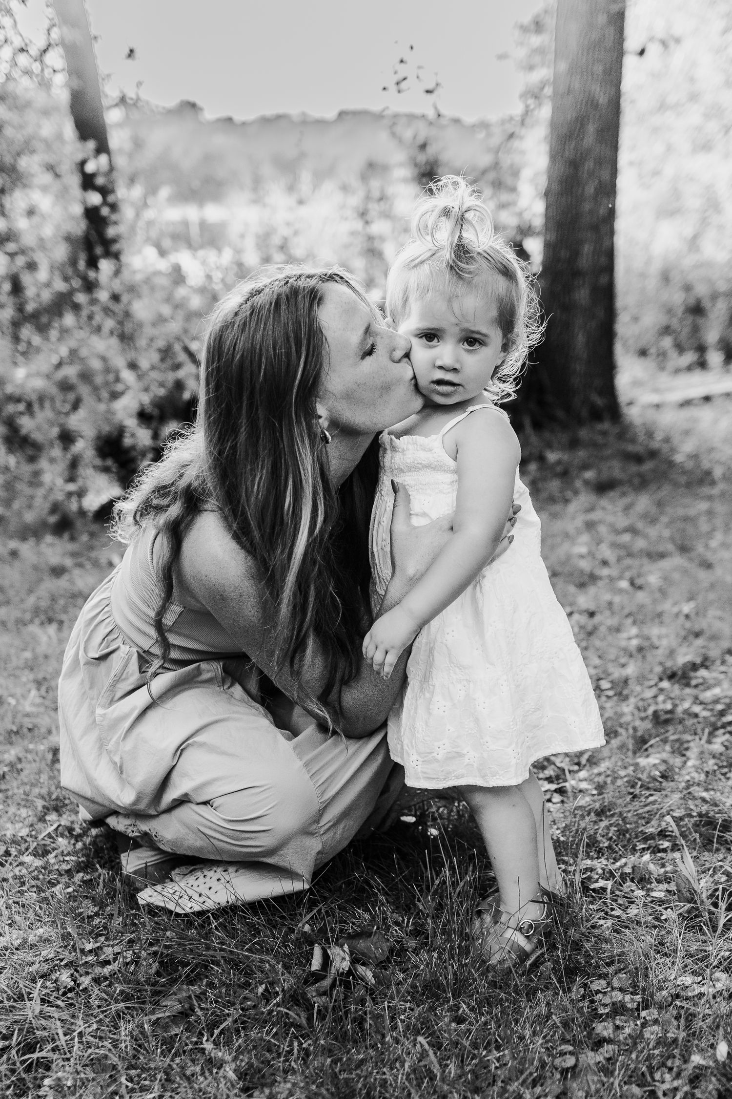 A tender black and white portrait of a parent and child sharing an intimate moment outdoors.