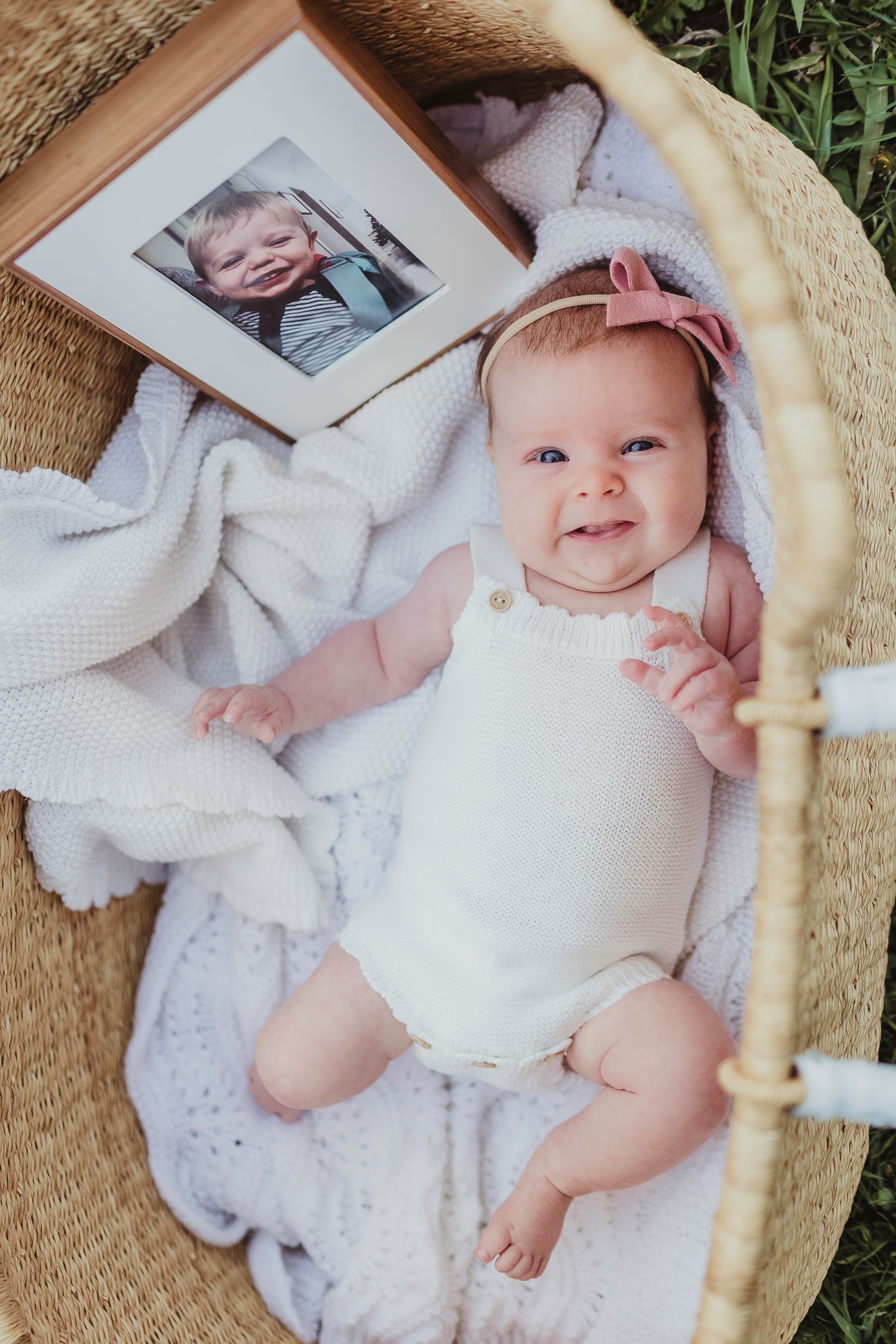 Sweet baby in white clothing lying on a textured blanket during a photo session.