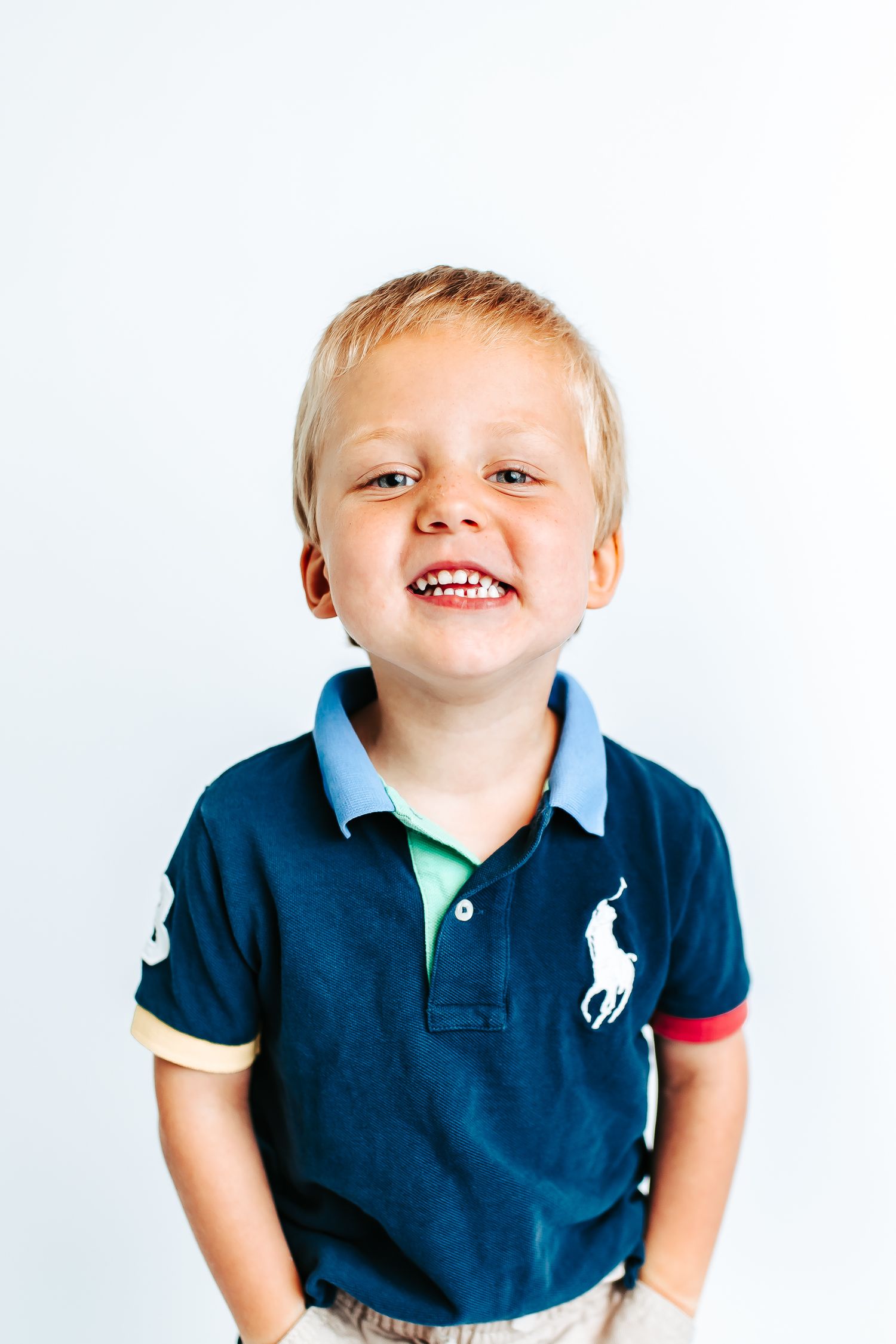 Cheerful poses in a navy blue polo shirt against a white backdrop.