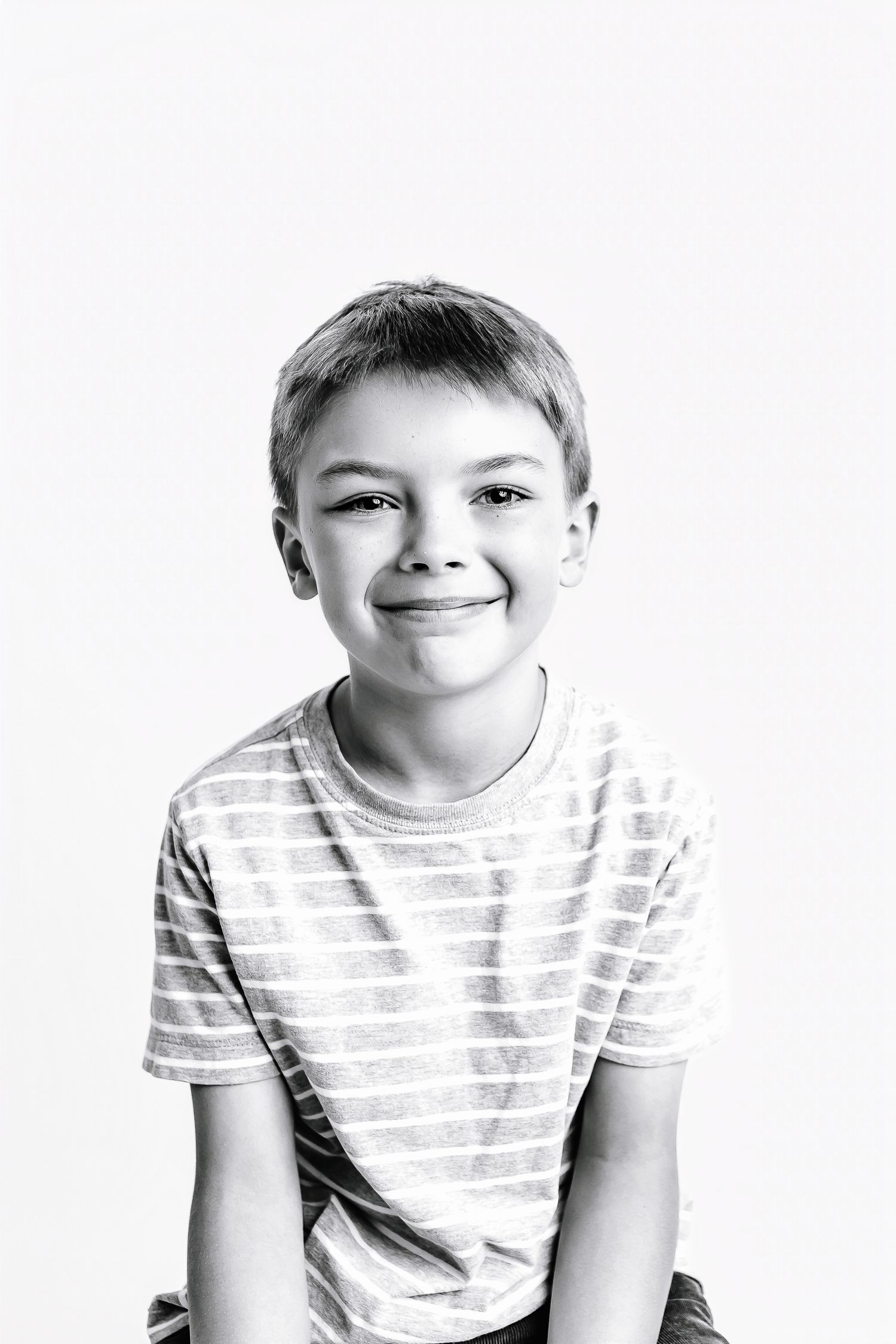 Child in striped t-shirt making playful expressions in black and white portrait series.