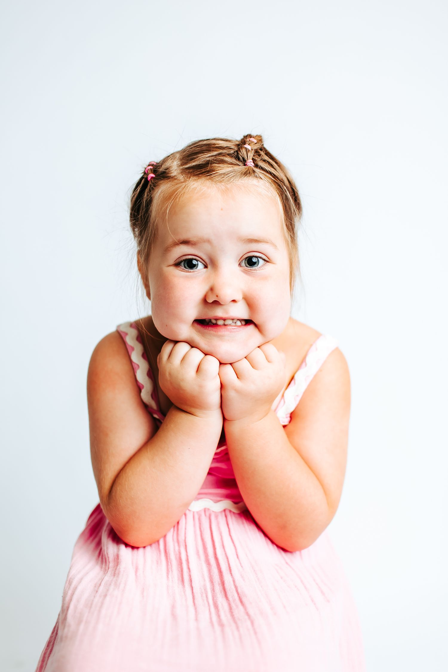 Studio portraits showing excited expressions in pink summer dress.
