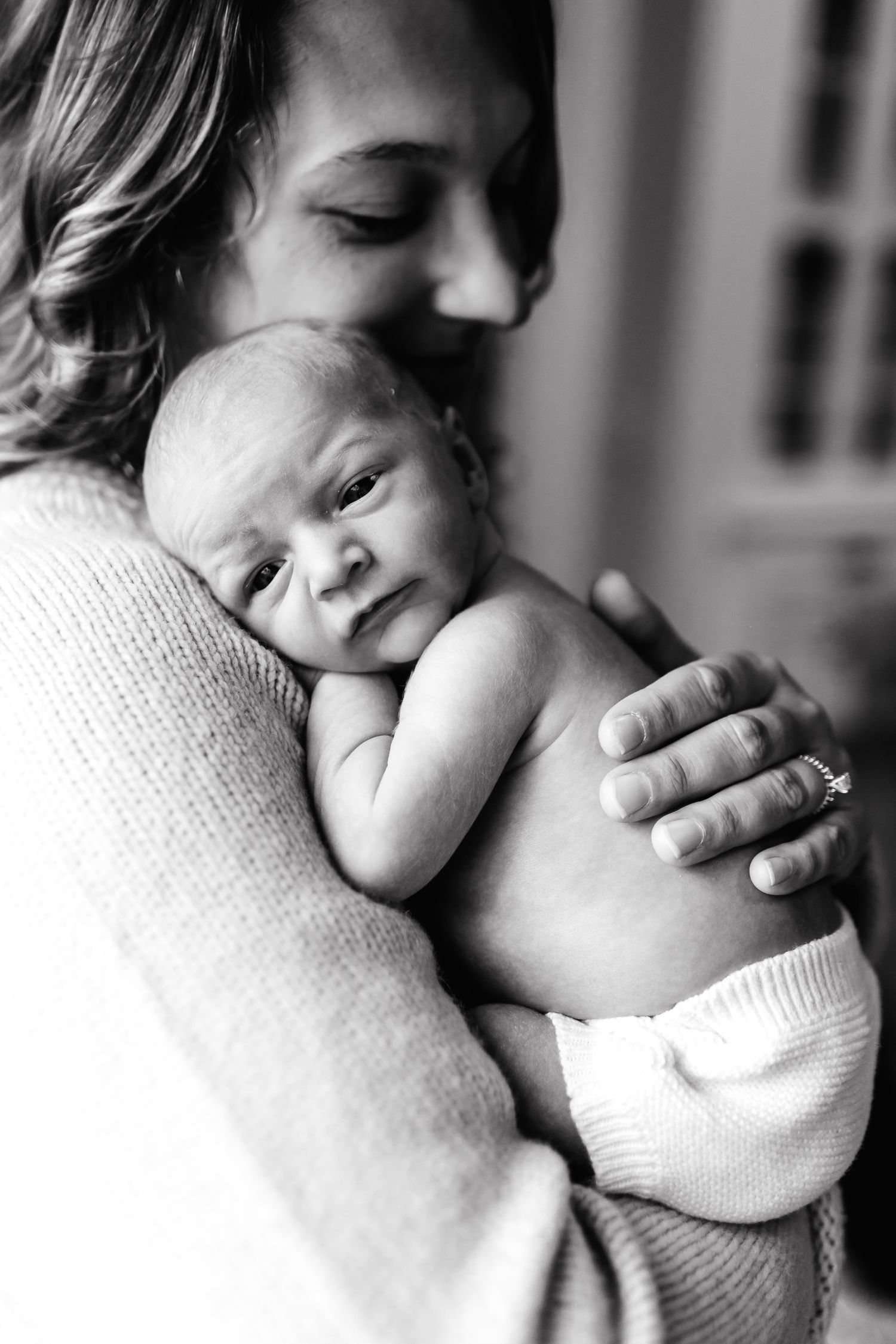 Intimate black and white portrait of tender moment between parent and newborn baby.