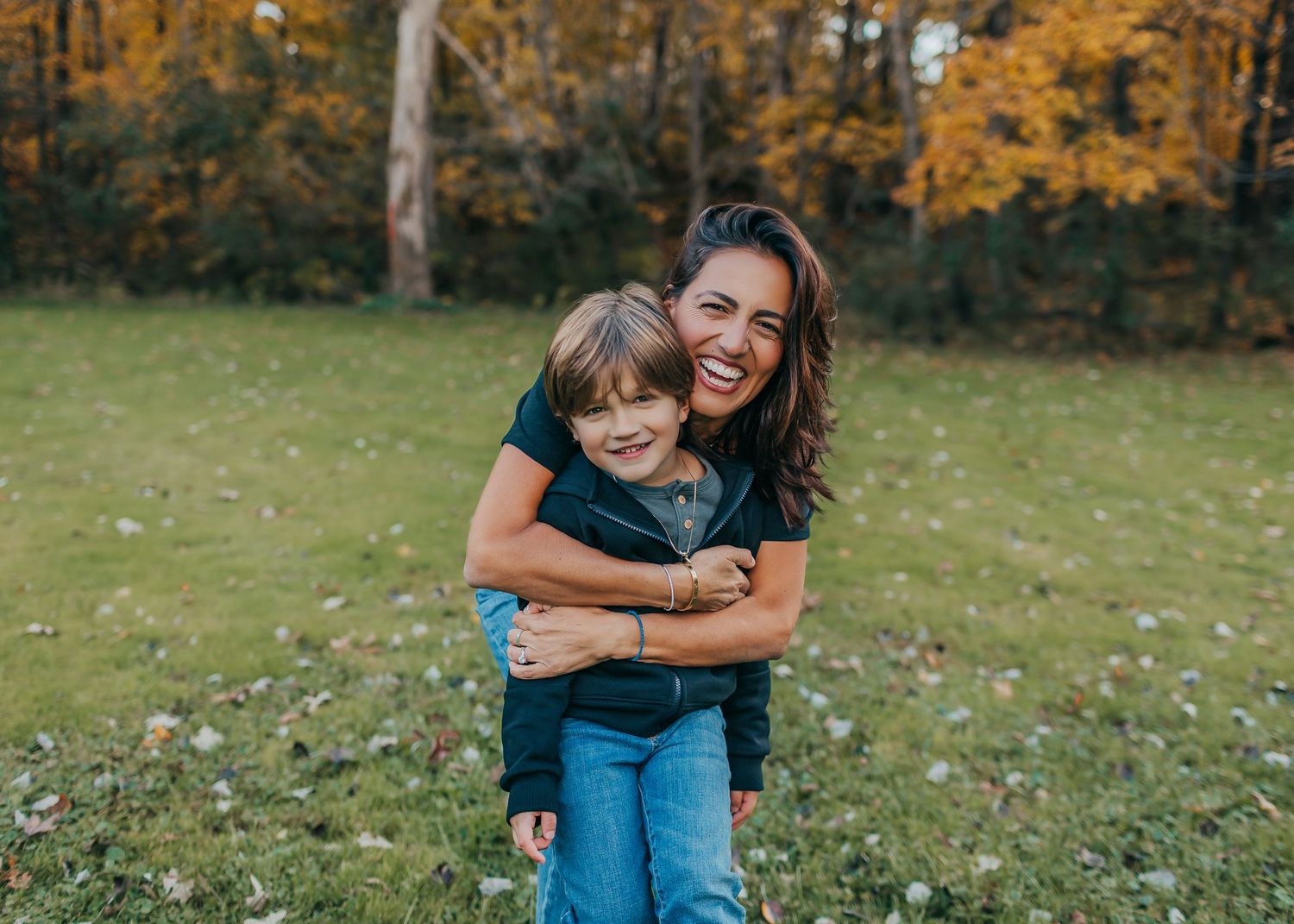 Mother and child sharing joyful moment together in autumn park with golden foliage.
