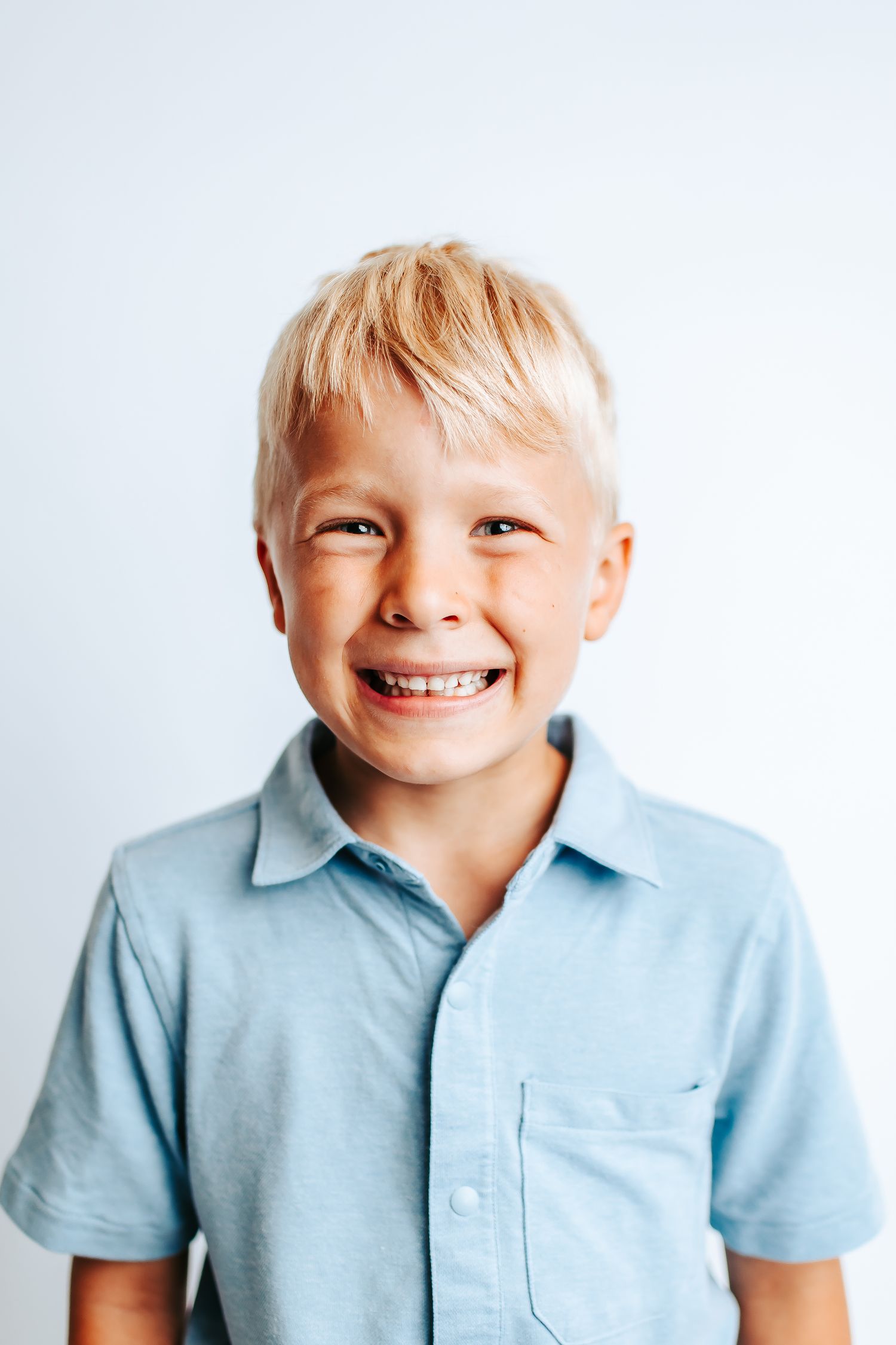 A series of four close-up photos showing a child in a light blue polo shirt making different playful expressions.