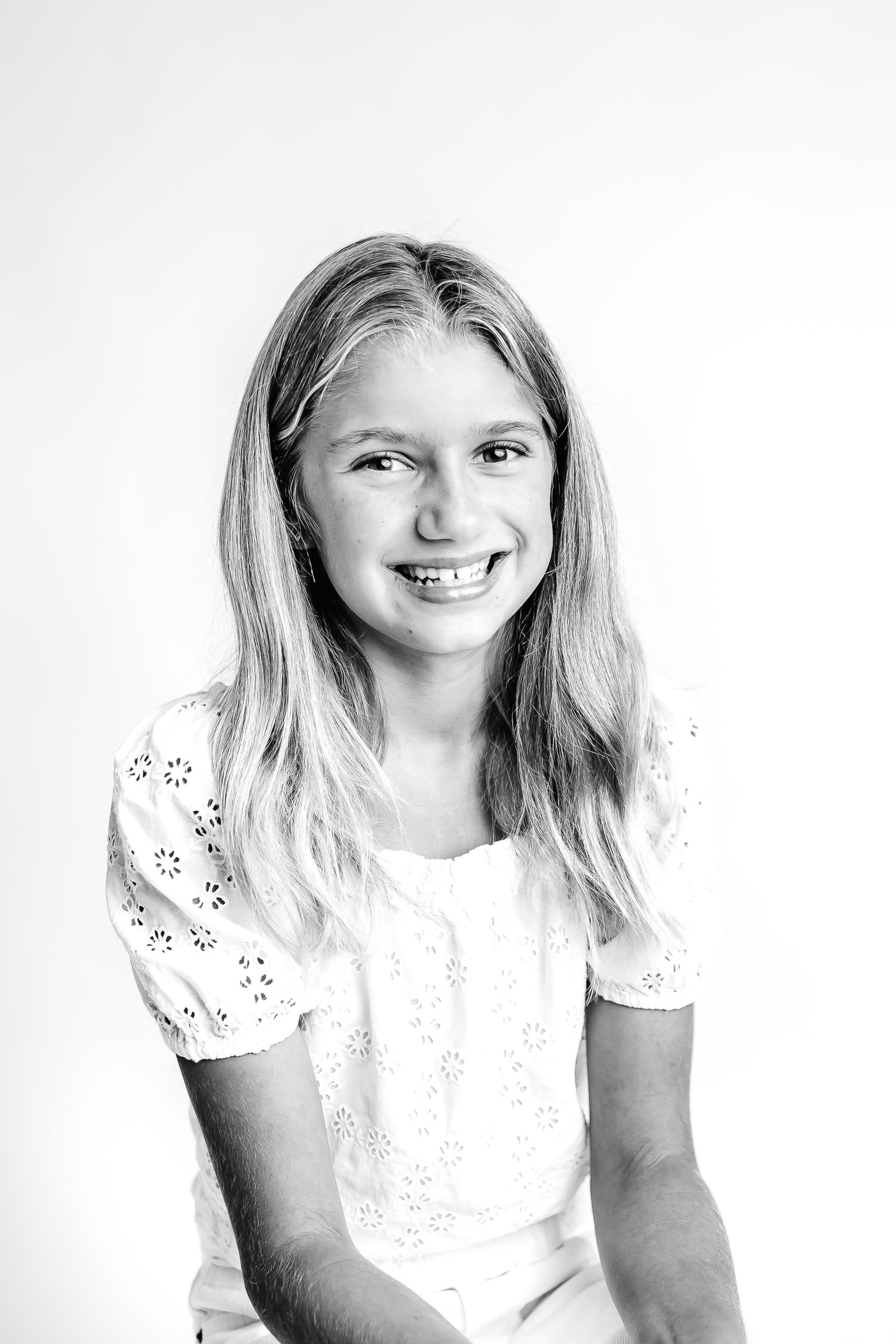 Three black and white portraits of a young person in a white lace top smiling at the camera.