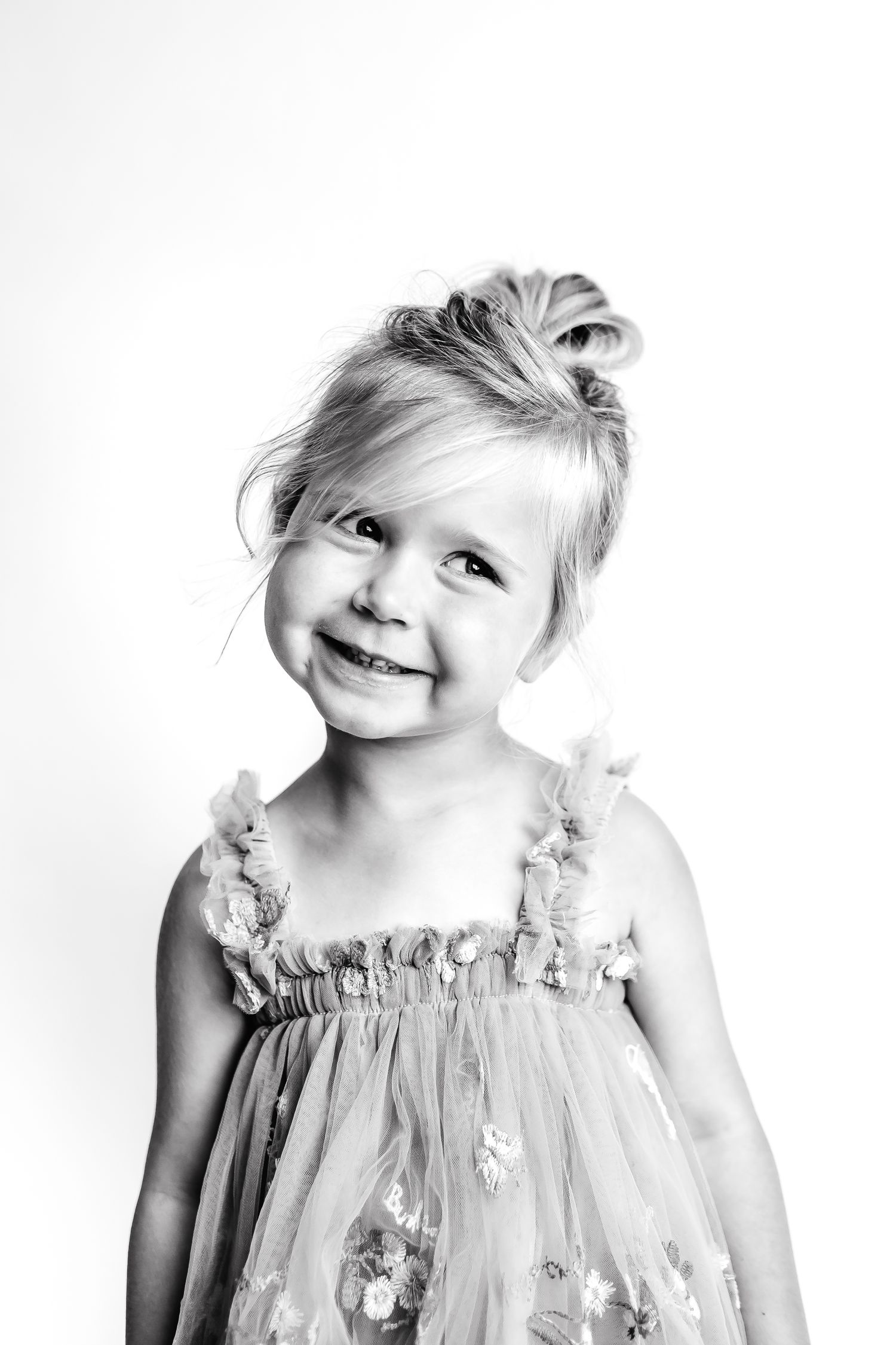 Five black and white portraits of a child in a ruffled dress making playful expressions.
