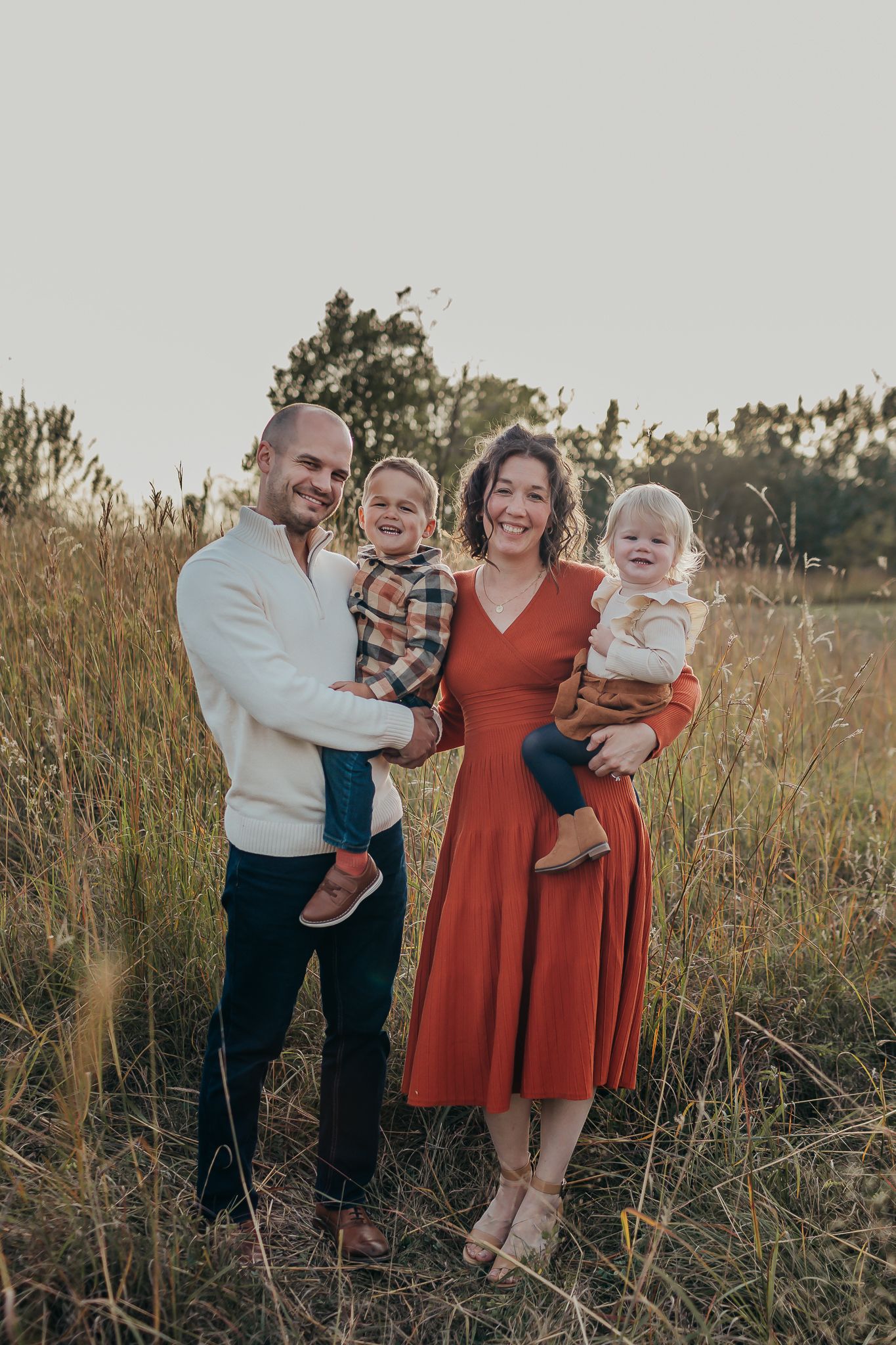 Family portrait in field at sunset with rust dress and casual attire.