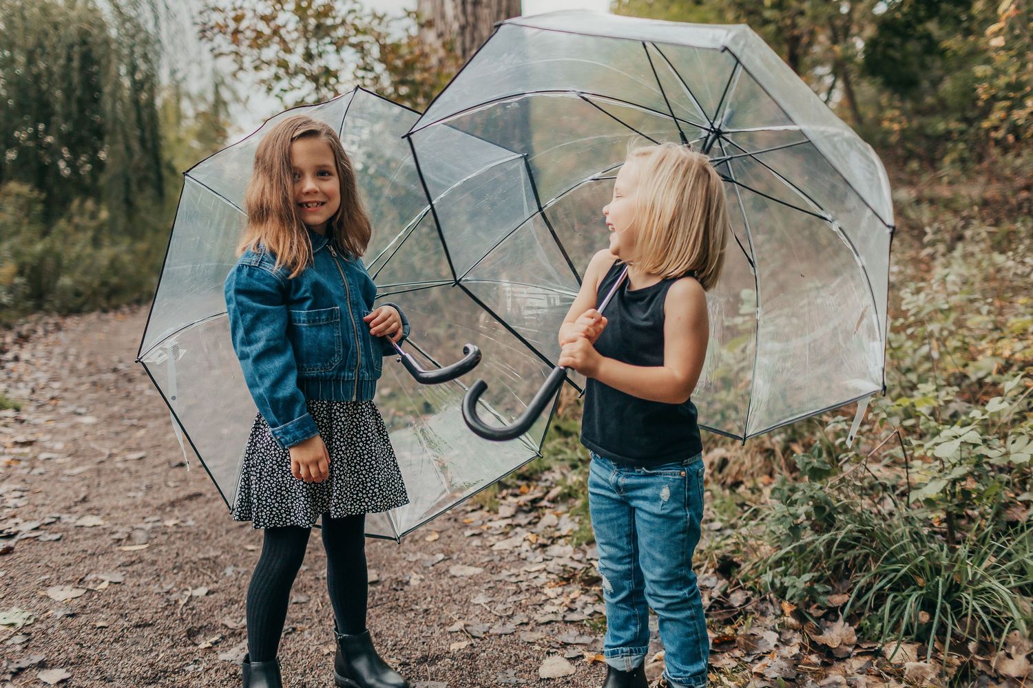 Family enjoying a rainy day walk with clear umbrellas in a garden setting.