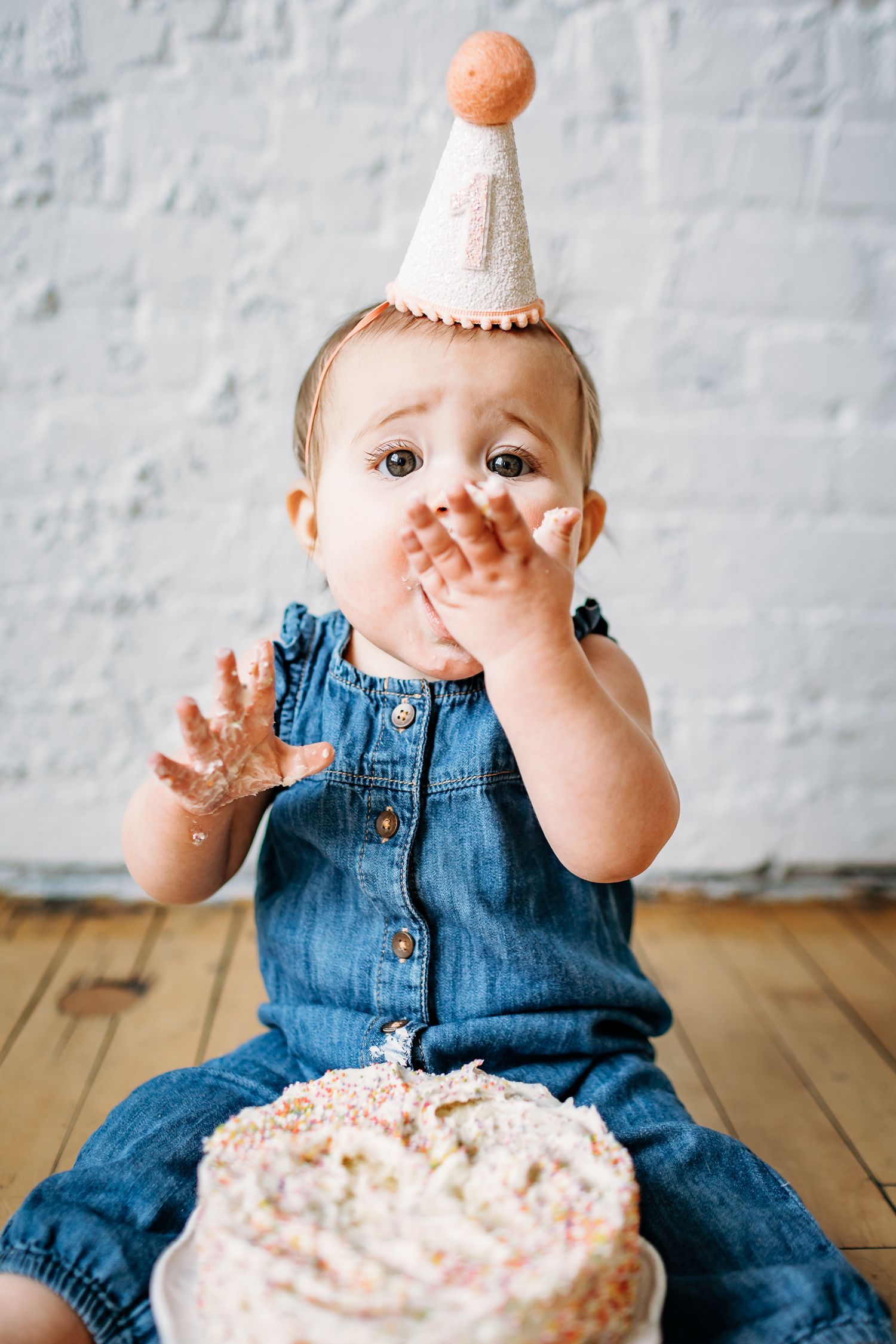 Five photos of a baby in denim overalls celebrating with a birthday cake.