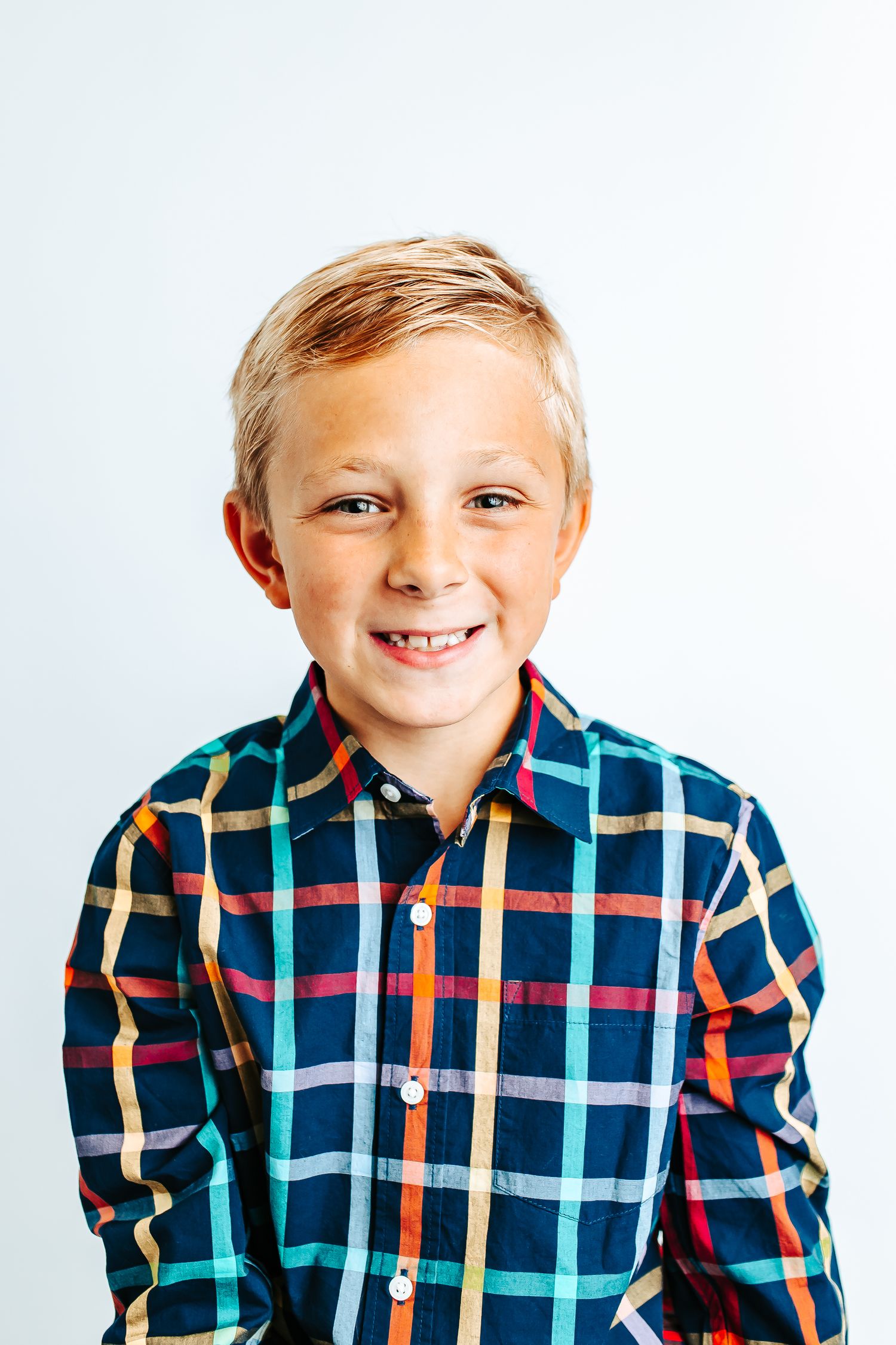 Collage of four similar photos showing a child wearing a blue and orange plaid button-down shirt against a white background.