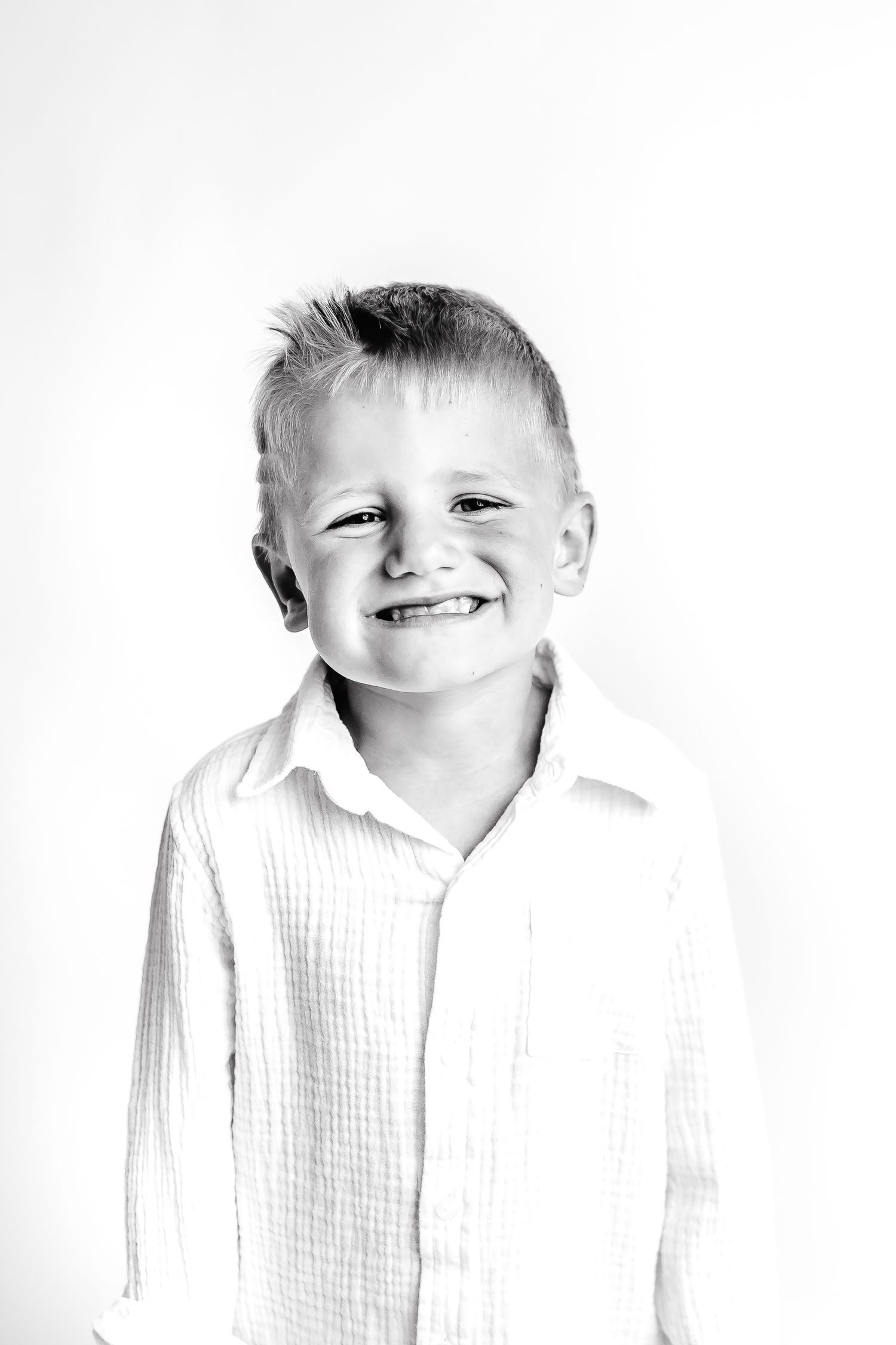 Four black and white photos of a young child in a white shirt showing different expressions and poses.